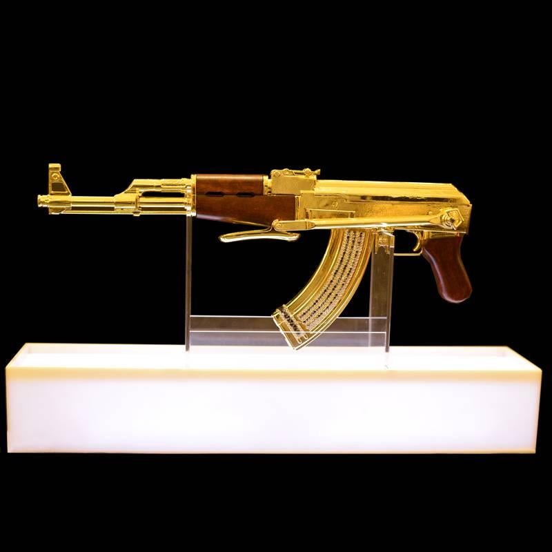 Fusil d'assaut AK-47 en finition dorée. Non fonctionnelle
Art sculpture démilitarisée:: 2016. 
Pièce authentique en édition limitée::
numérotée 08/15. Finition à la feuille d'or. 
Base sur plexiglas avec lumière LED
et système de variation de