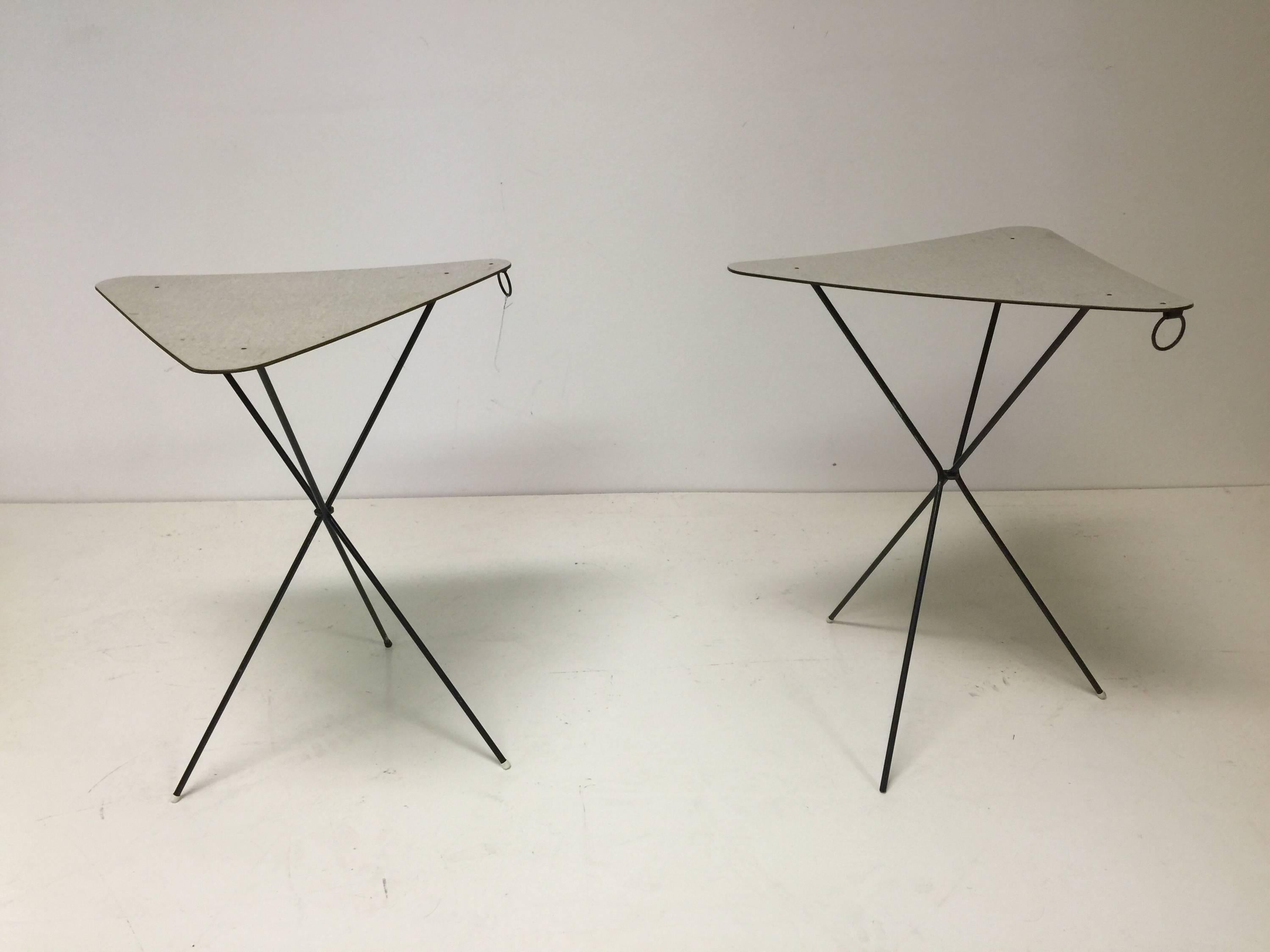 A pair of French, 1950s triangular cocktail tables by Mathieu Matégot with formica tops and black enameled iron tripod legs. The tables fold up for easy carrying with attached rings.