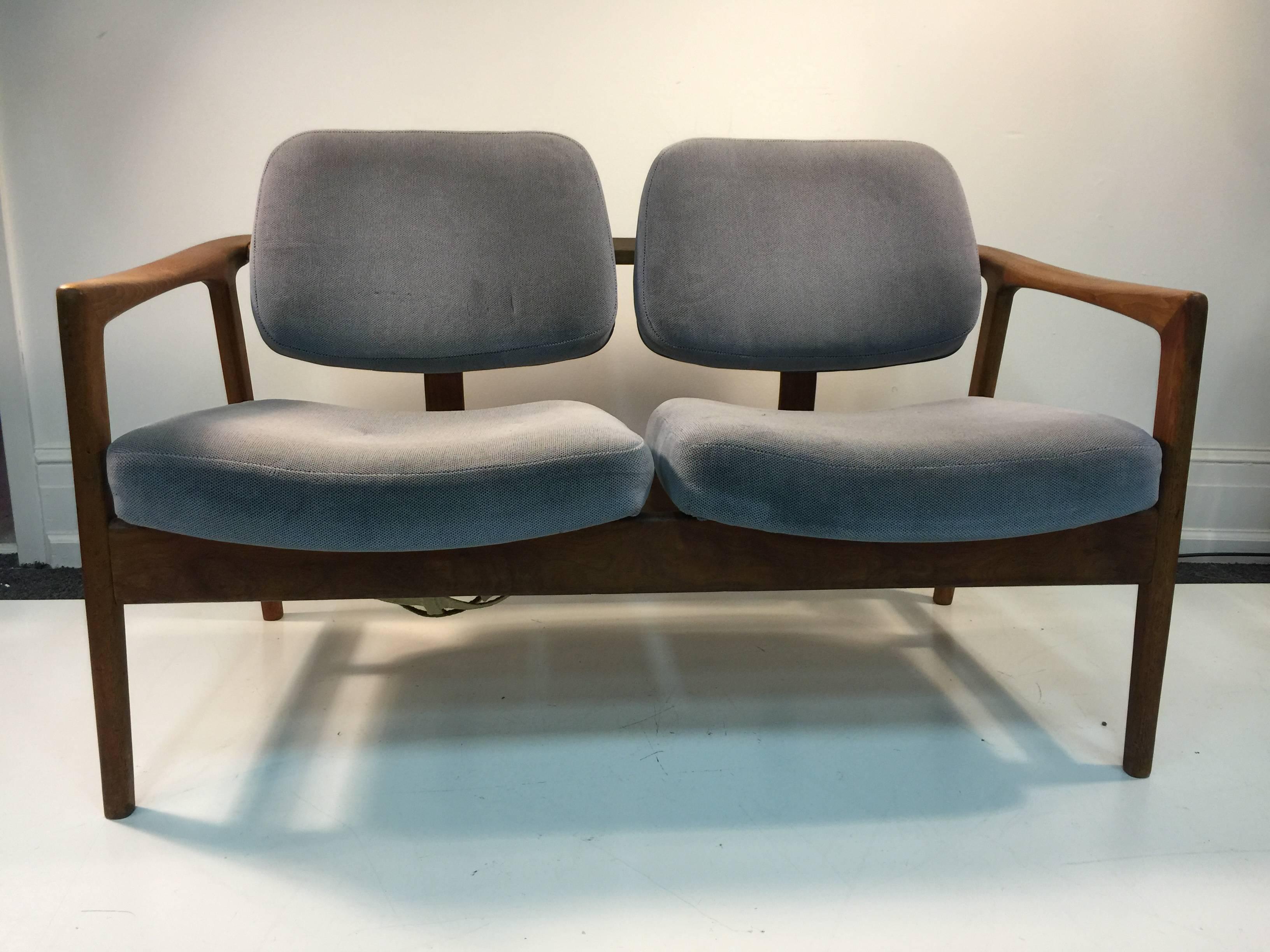 A pair of double seat Scandinavian Modern teak settees in the manner of Finn Juhl, circa 1970s.