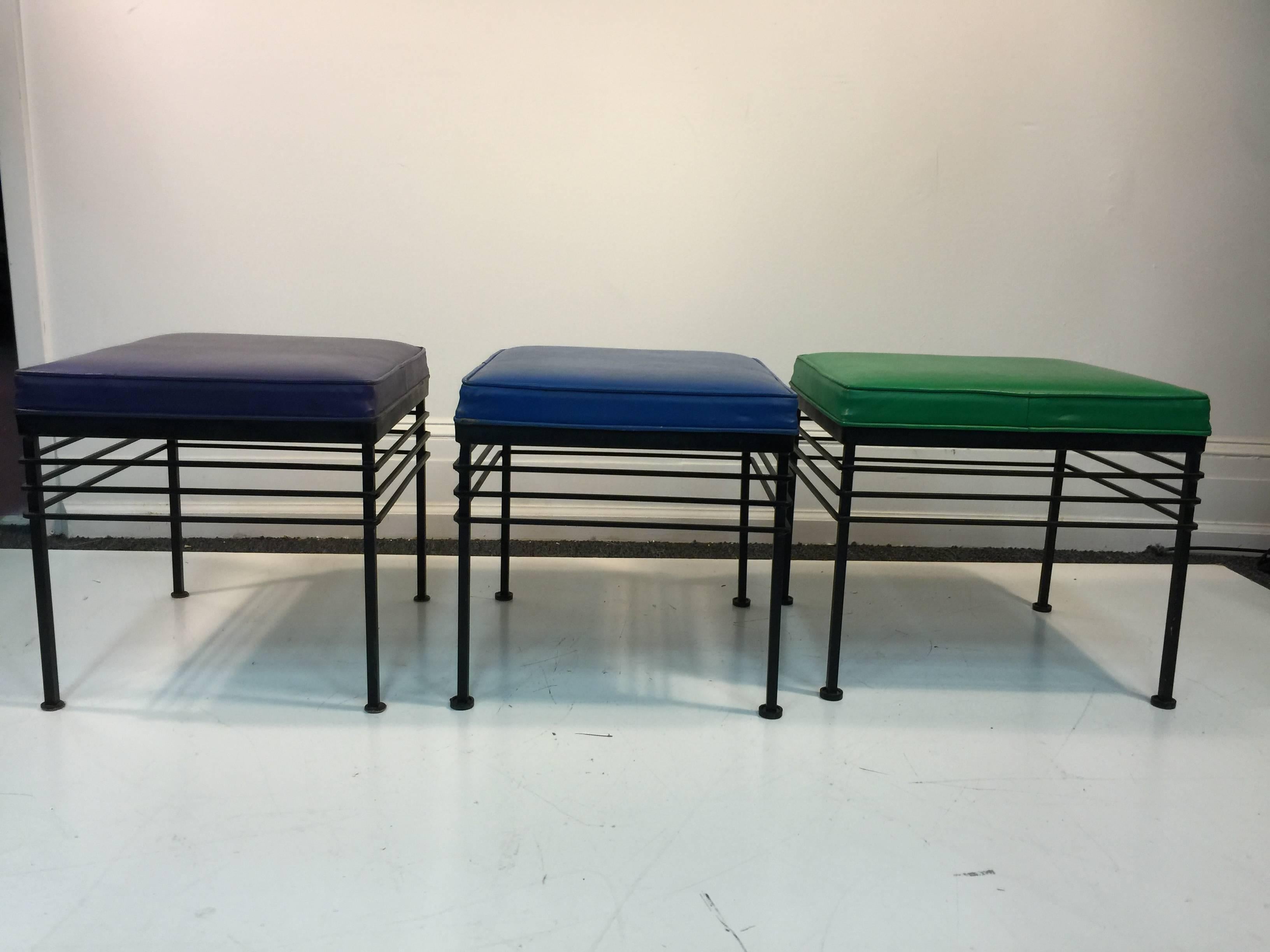 A super trio of stools or benches in blue, green, and purple vinyl upholstery with wrought iron bases in the manner of Paul McCobb, circa 1970.