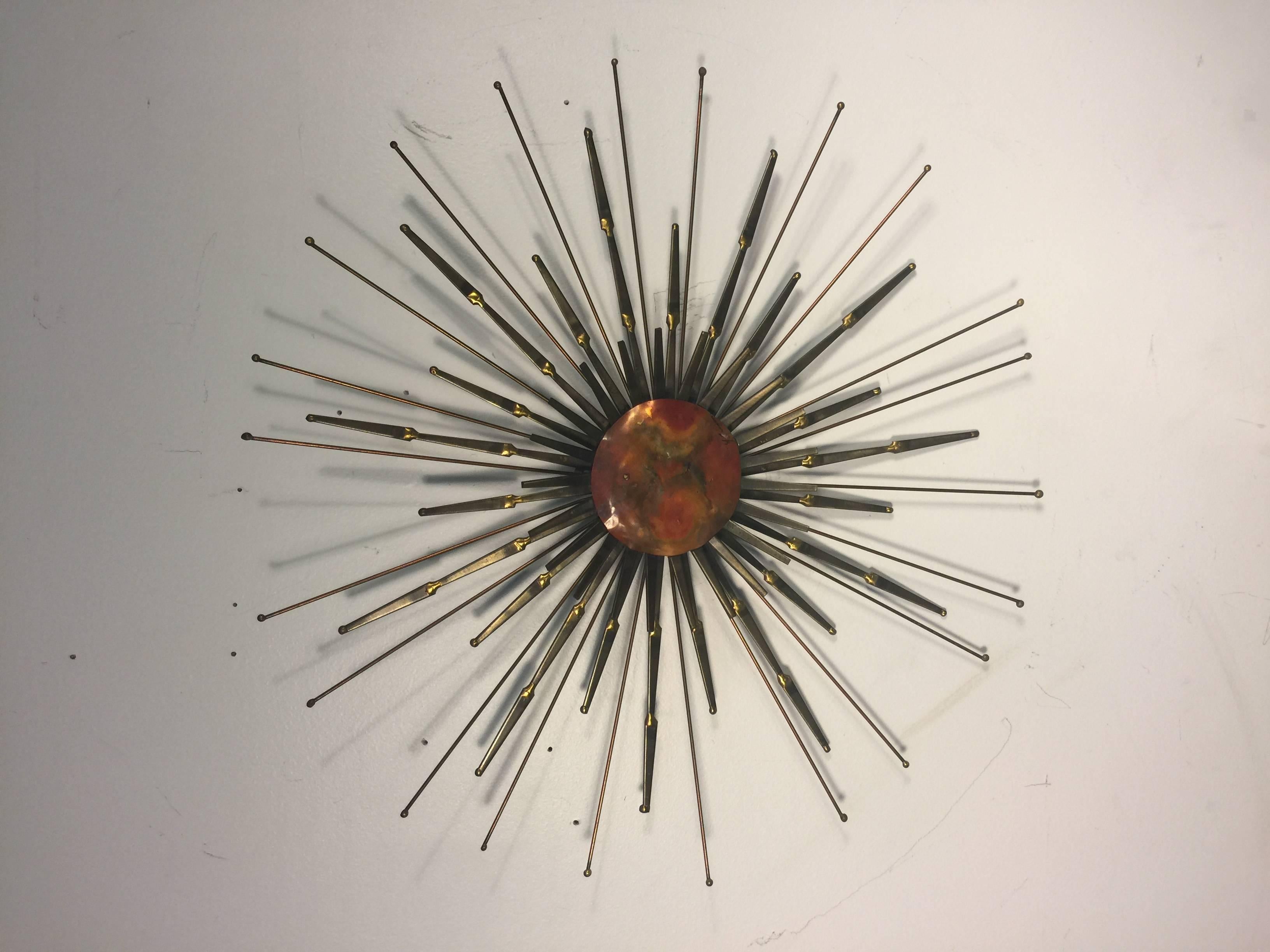 A striking sunburst wall-mounted sculpture with flat nailhead design and colorful mixed-metal center by Curtis Jere, circa 1970.