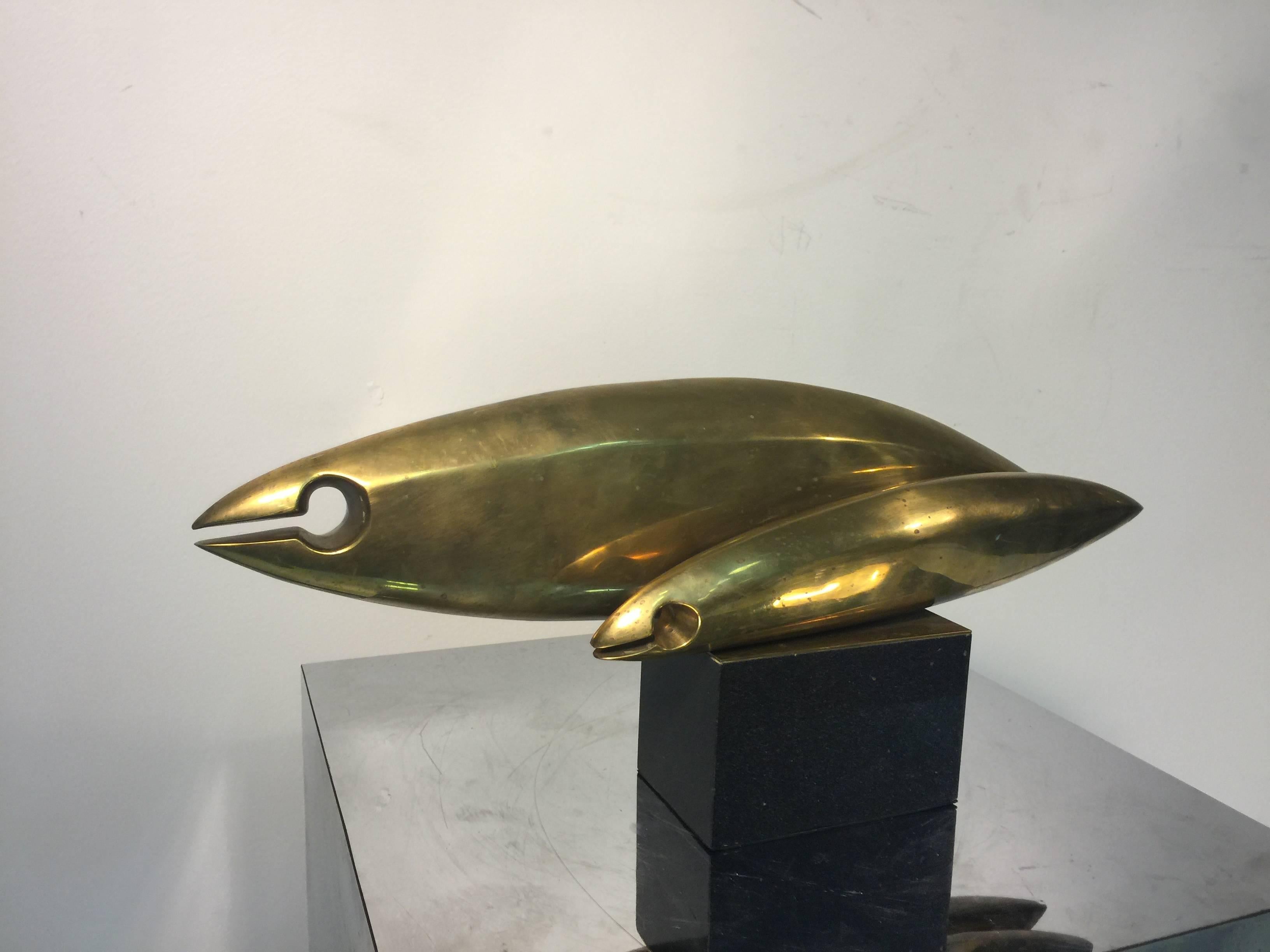 A fantastic modernist brass sculpture in the style of Jean Arp of two swimming fish on a black marble base.