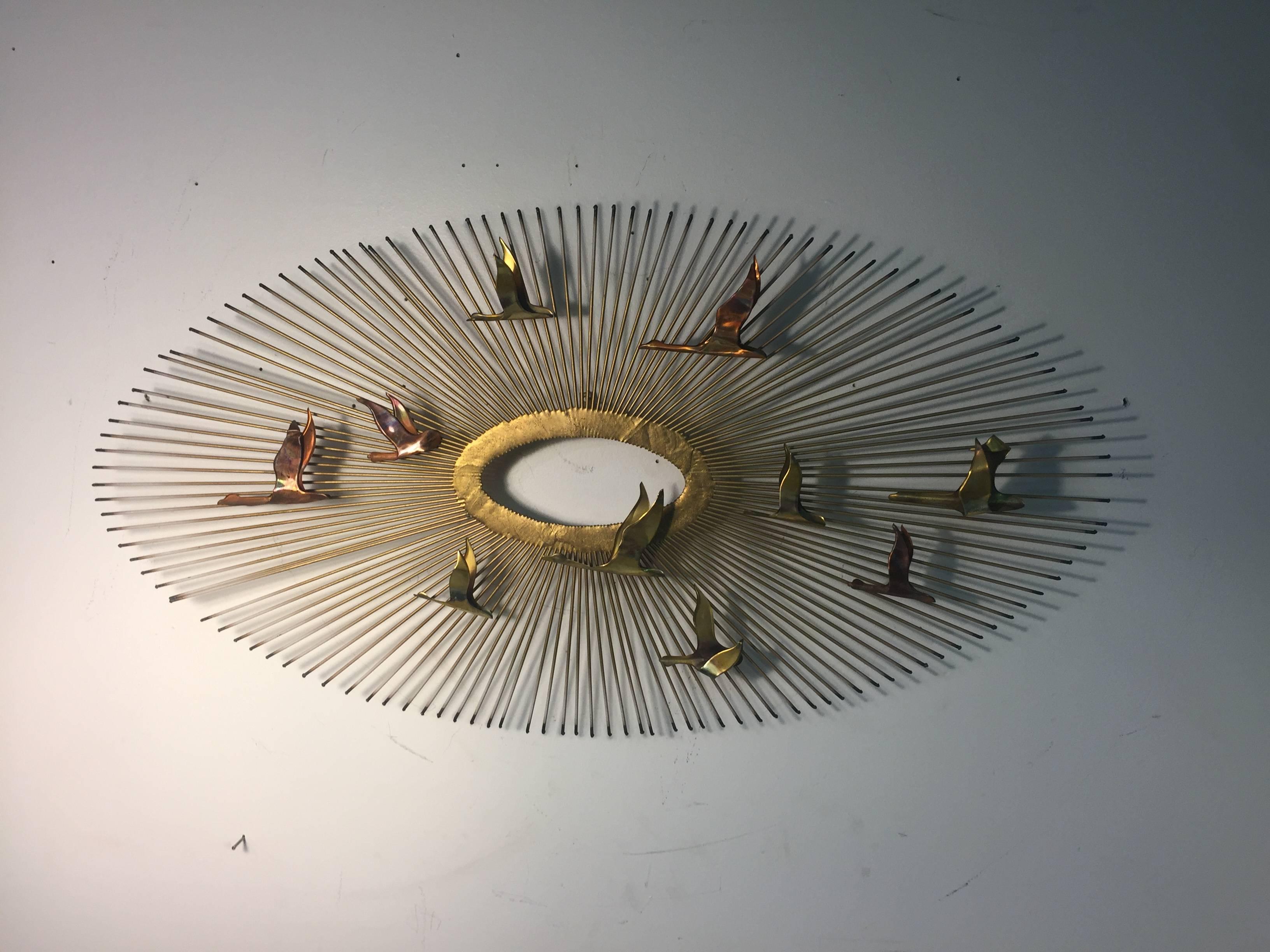 A beautiful Curtis Jere mixed-metal starburst wall-mounted sculpture with flying birds, circa 1980.
