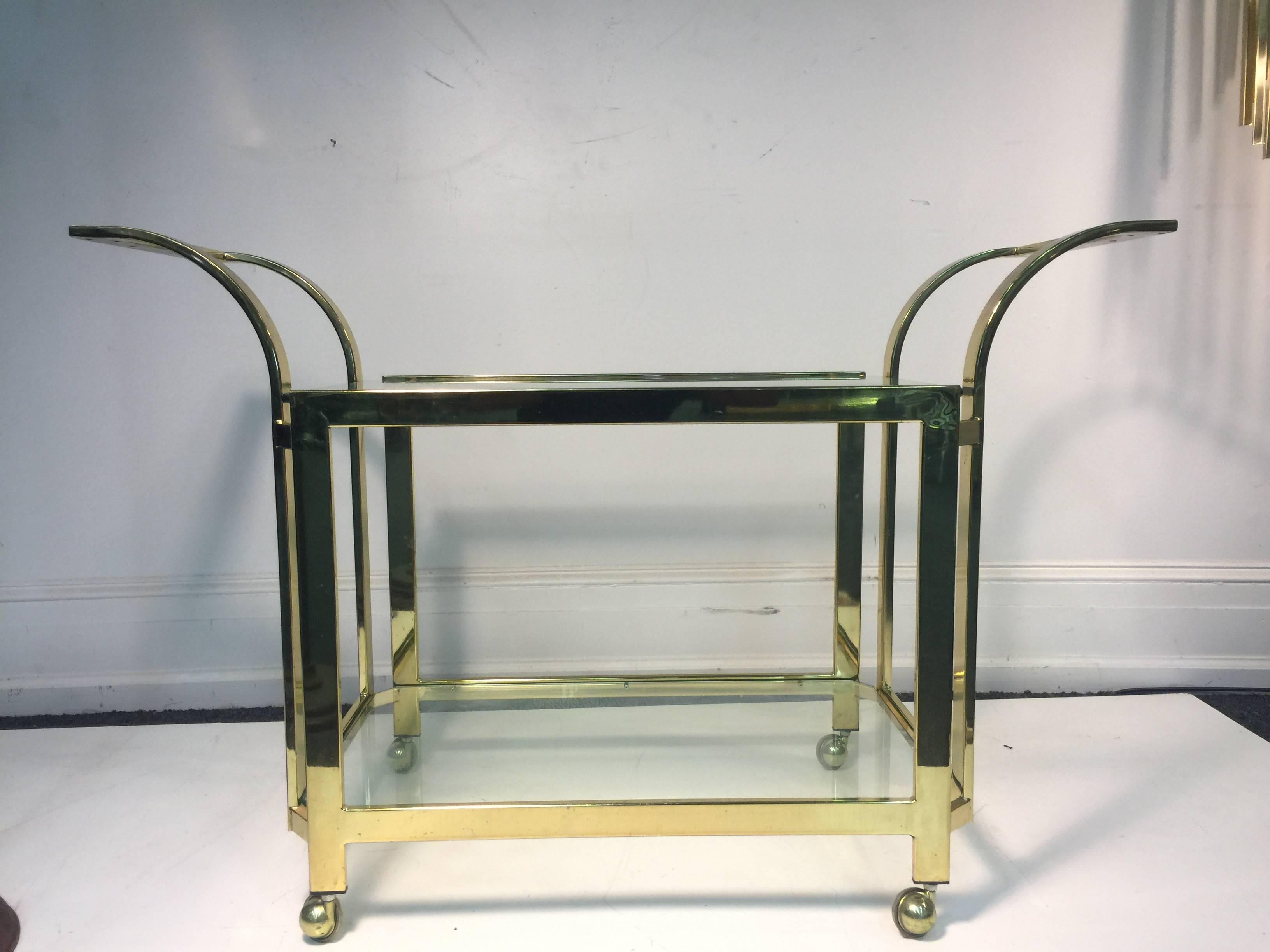 A beautifully designed two-tier brass and glass bar or tea cart by Milo Baughman, circa 1970. Good condition with age appropriate wear.