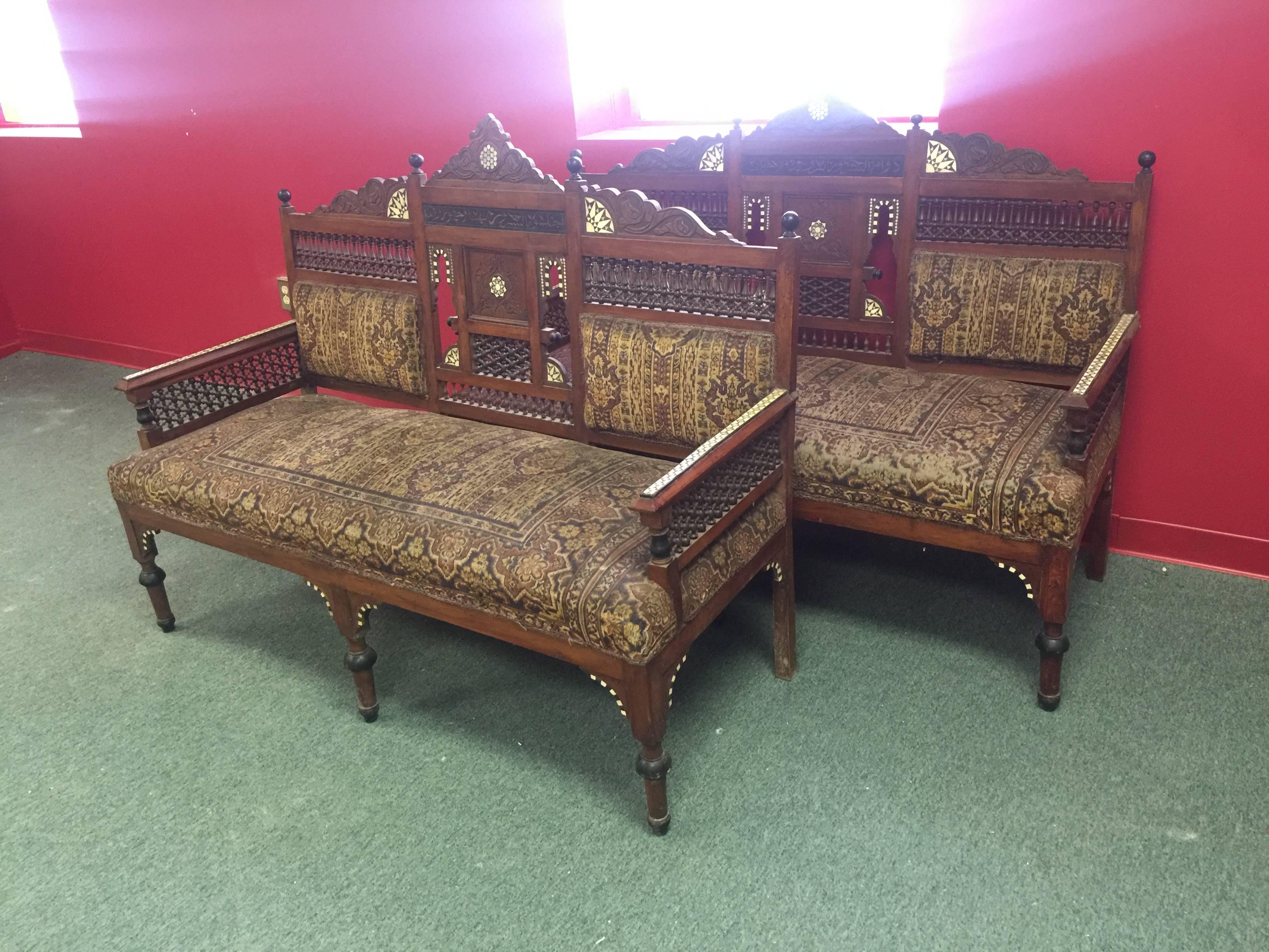 A pair of outstanding 19th century hand-carved Moorish settee or chairs with beautiful Islamic writing, fine detail, and original fabric in the manner of Carlo Bugatti. Good condition with age appropriate wear.