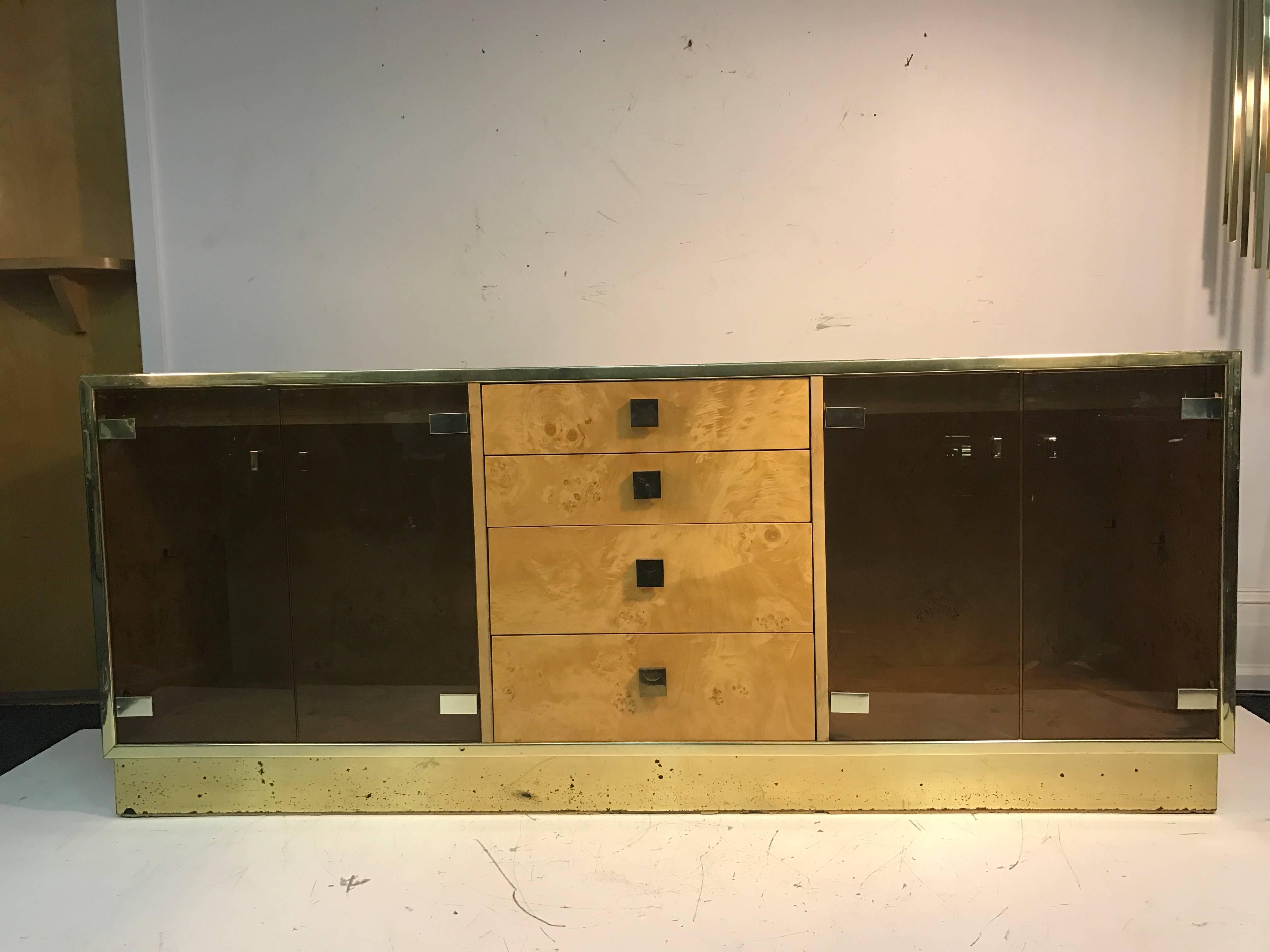 A magnificent burl wood sideboard, credenza, or cabinet with set of double glass doors, four drawers, and interior lighting by Milo Baughman. This versatile piece can be used for entertaining, storage, or displaying your favorite items. Good vintage