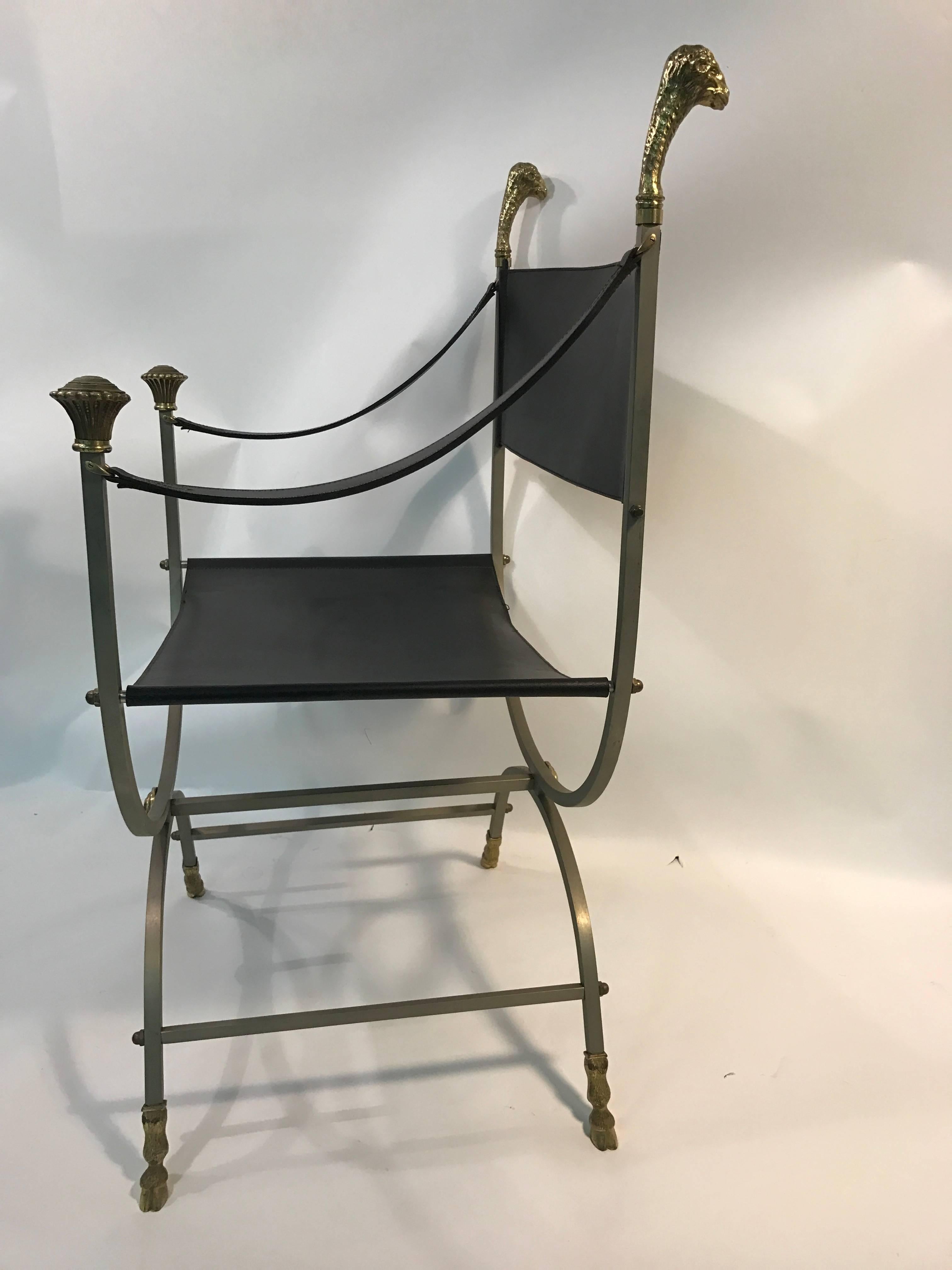 Striking steel and black leather chair with sculpted brass ram's head finials and hooves by Maison Jansen, circa 1960. Good vintage condition with some wear underneath the seat.