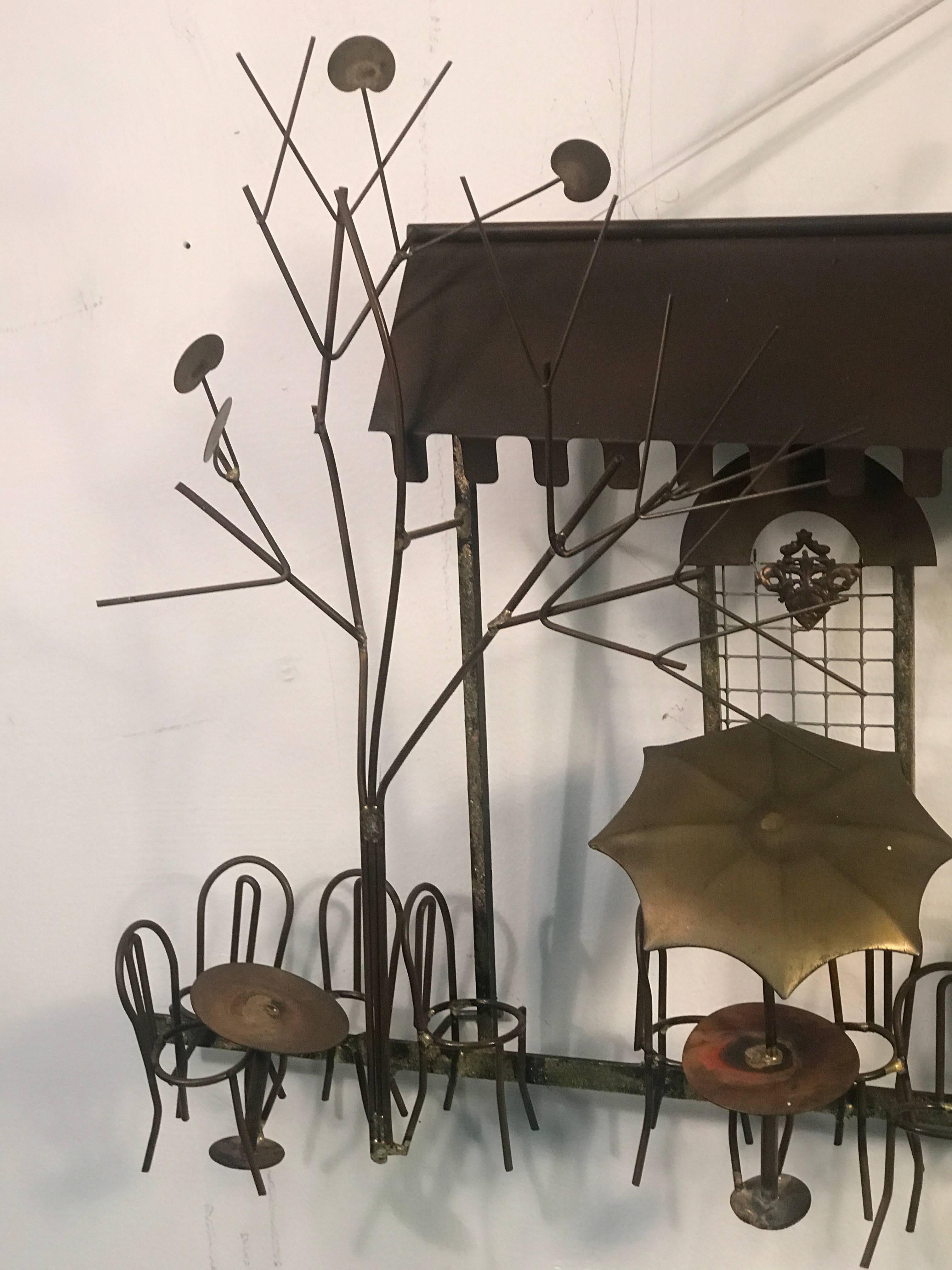 A wonderful copper and brass Curtis Jere wall sculpture of an outdoor cafe with careful attention to detail that includes: bistro tables and chairs, umbrellas, trees and arched windows. In great vintage condition with some wear appropriate with age.