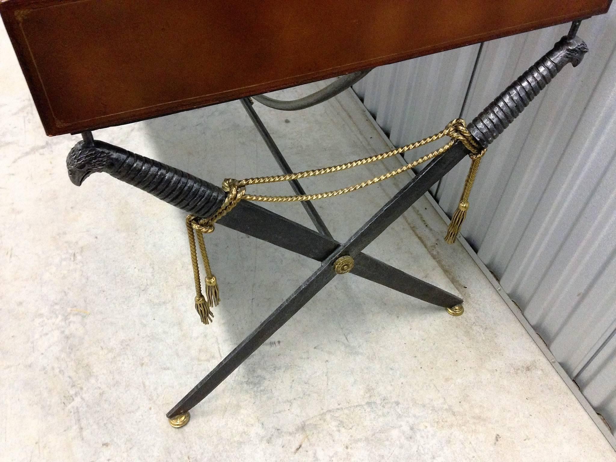 Interesting, High End desk comprised of iron and bronze saber legs with eagle head handles and brass braided tassels base. A beautiful cognac leather top decorated with gold borders. Having four drawers with solid brass decorative handles this is a