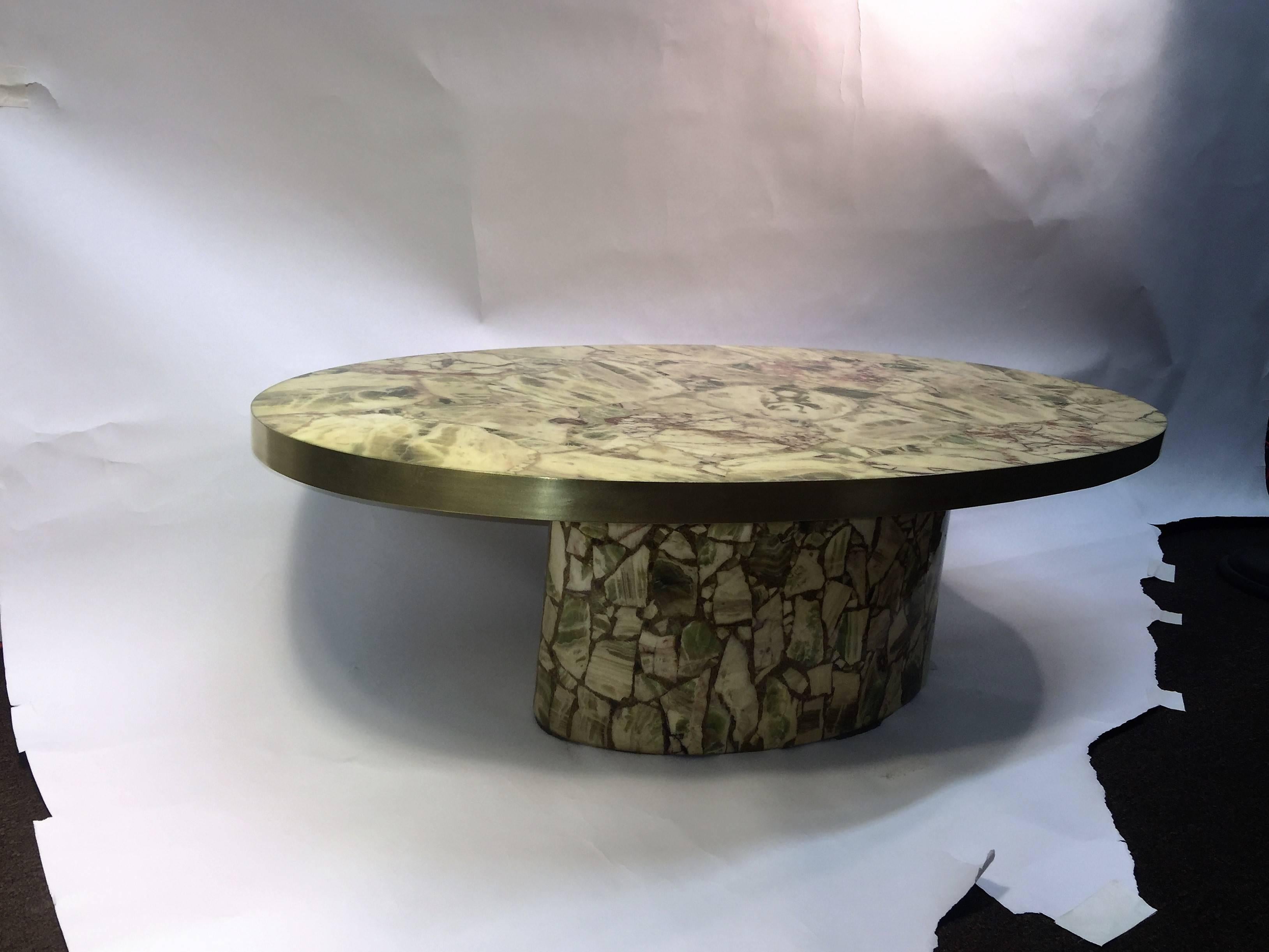 1970s great oval coffee table comprised of specimens of green onyx encased in Resin. The oval top inset in a brushed brass frame seated upon a pedestal base. Very high end and substantial table designed and created in Italy with fantastic colored