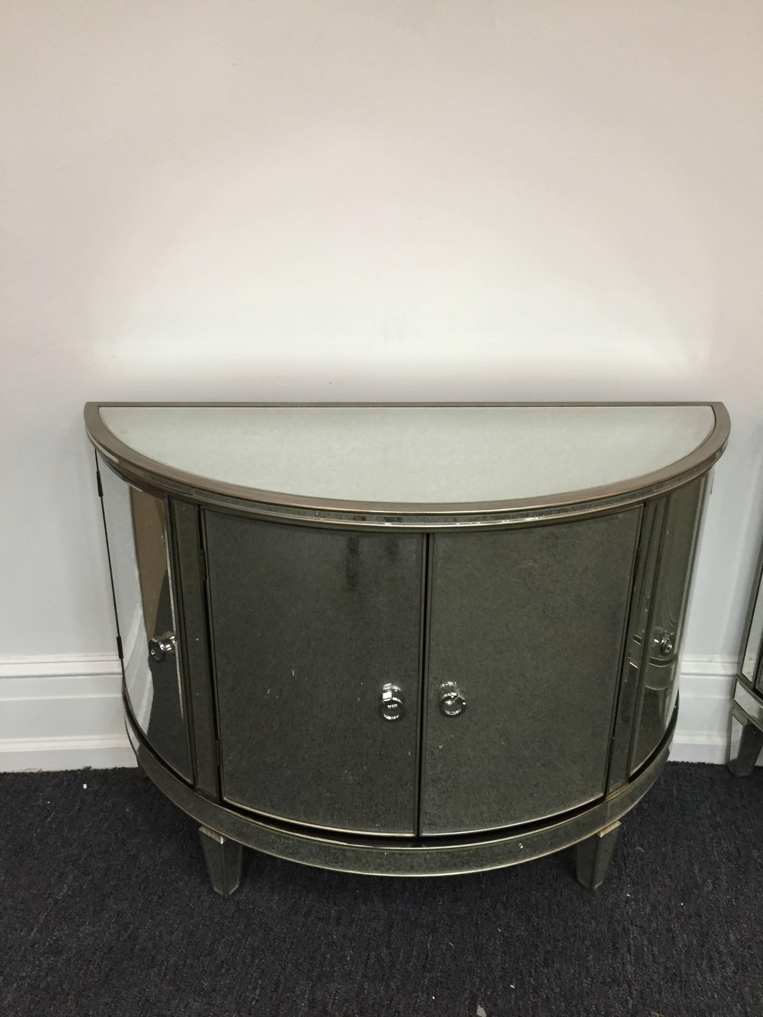 A pair of custom-made mirrored demilune mirrored commodes or chests with curved doors.