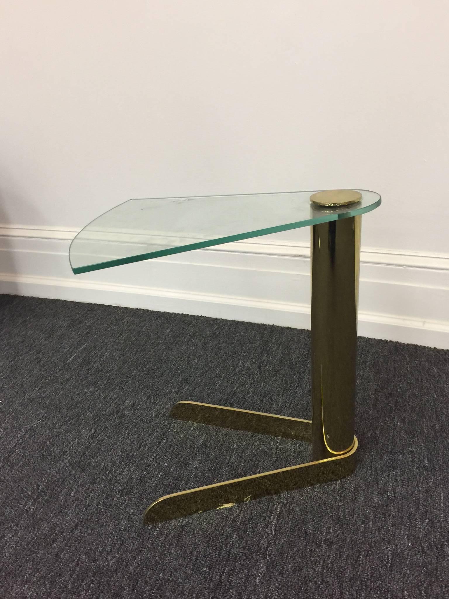 A Karl Springer style sculptural wedge shaped side or drink table with polished green edged glass top and brass column base.
 