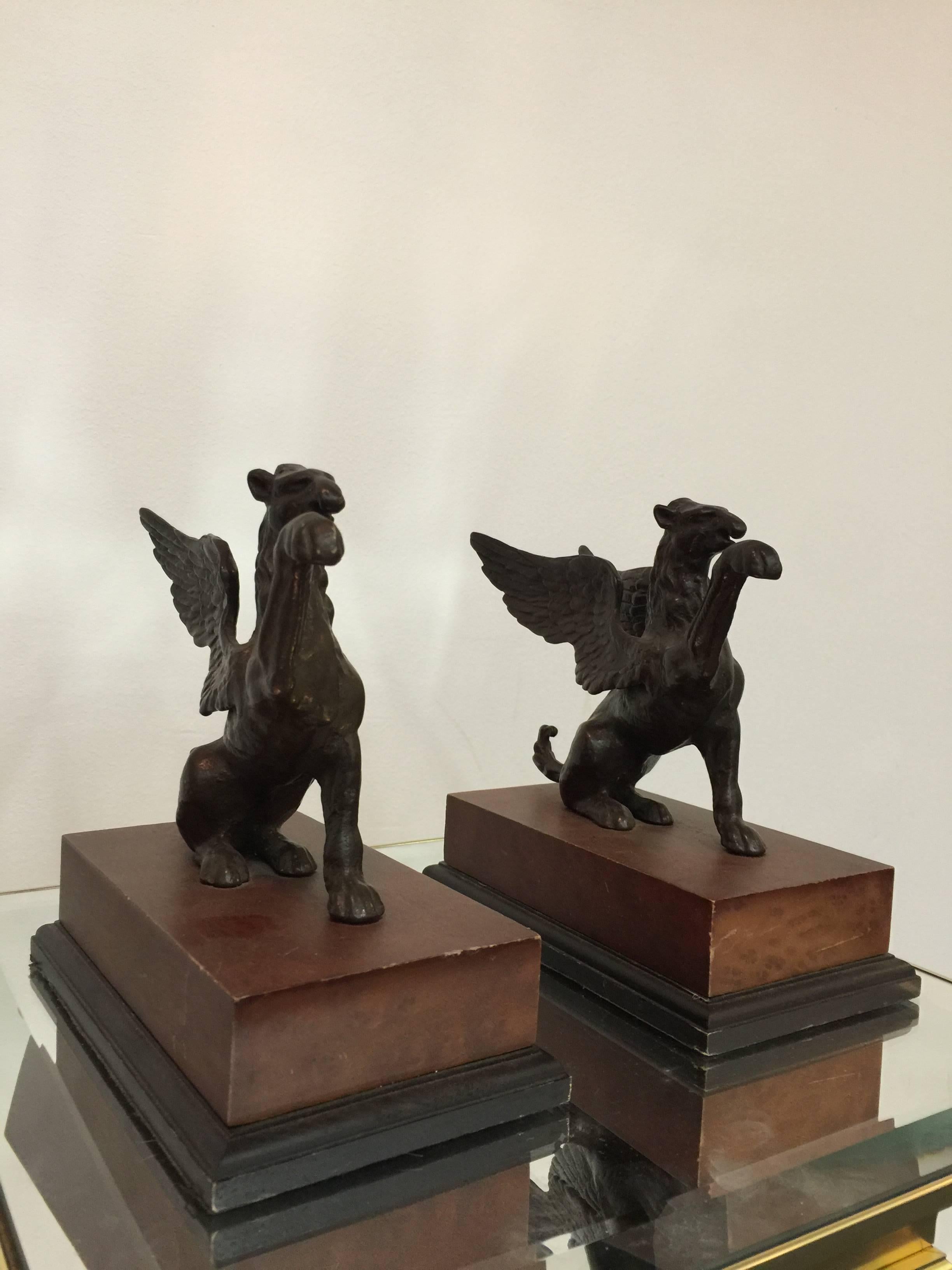 A pair of sculptural bronze griffin bookends on wooden bases.