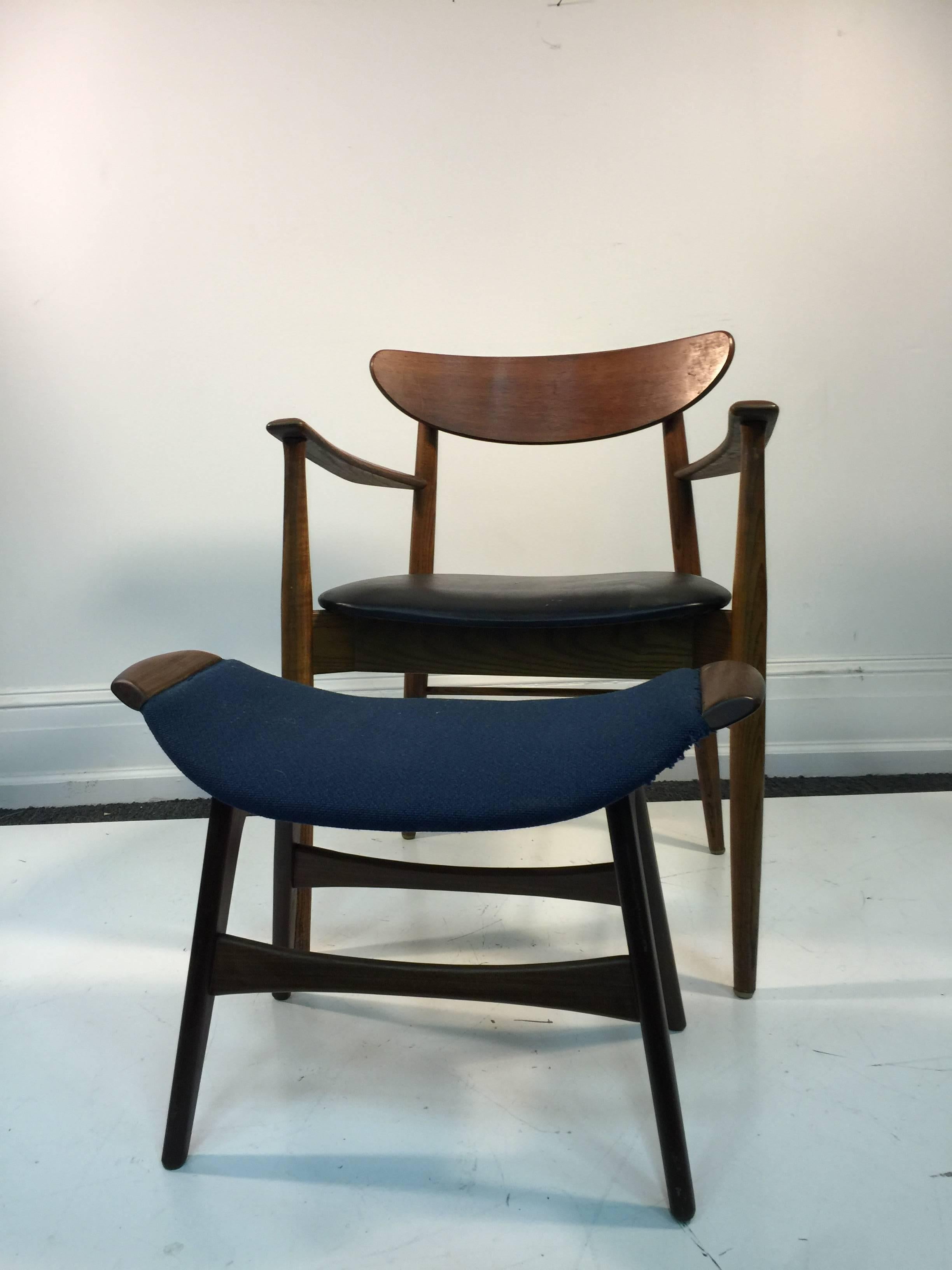 A Scandinavian Modern armchair and ottoman with tapered legs in the manner of Hans Wegner. Each piece is being sold separately. 

Ottoman: 26 W X 14 D x 15 H.
Chair: 32 W x 17 D x 24 H x 18 S.