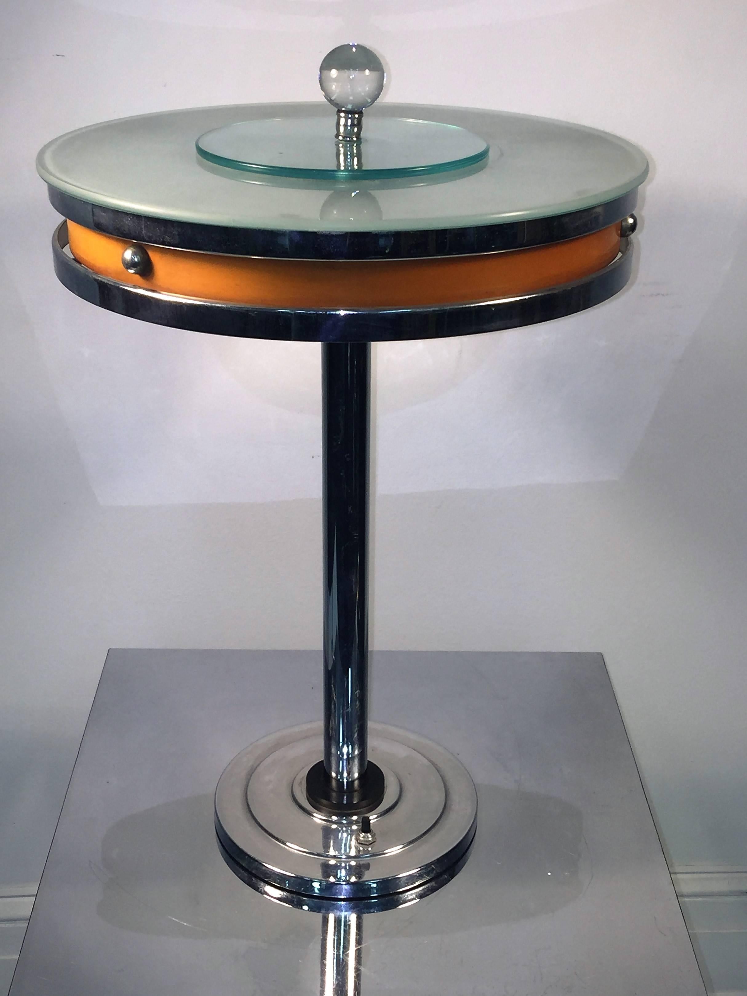 Glamourous yet Machine Age table lamp designed by Kurt Versen. Comprised of chromed brass stem and base, the round disc shaped shade is chromed and enamel brass as well. On the triple ring design base there is a black bakelite disc accent. The top
