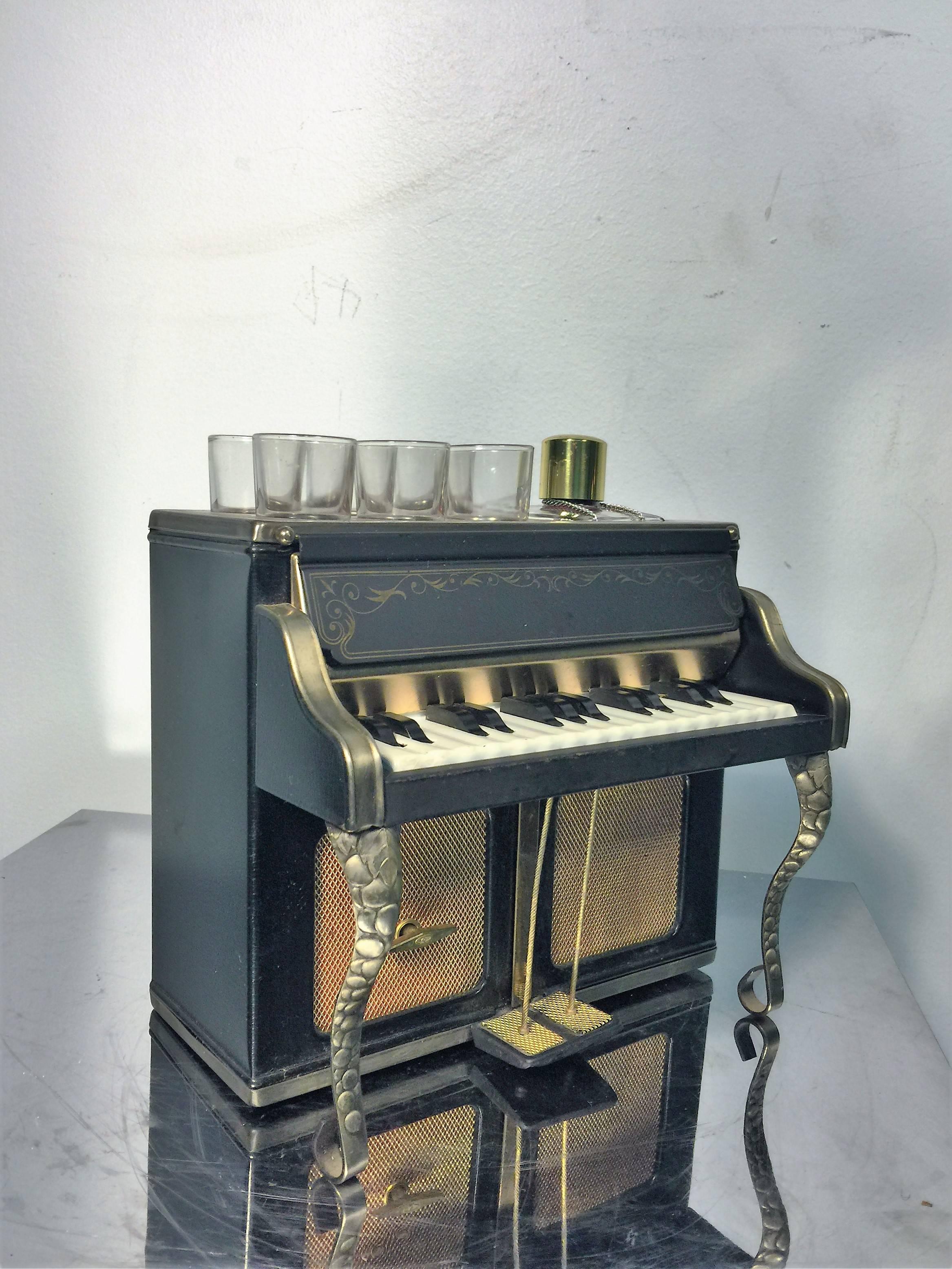 A great piano shaped musical bar made in the 1960s in Japan. Comprised of a cast phenolic keys, burnished and black enameled brass. You can wind the music box with the key at the foot of the pedals so that you can play ' drink to me only with thine