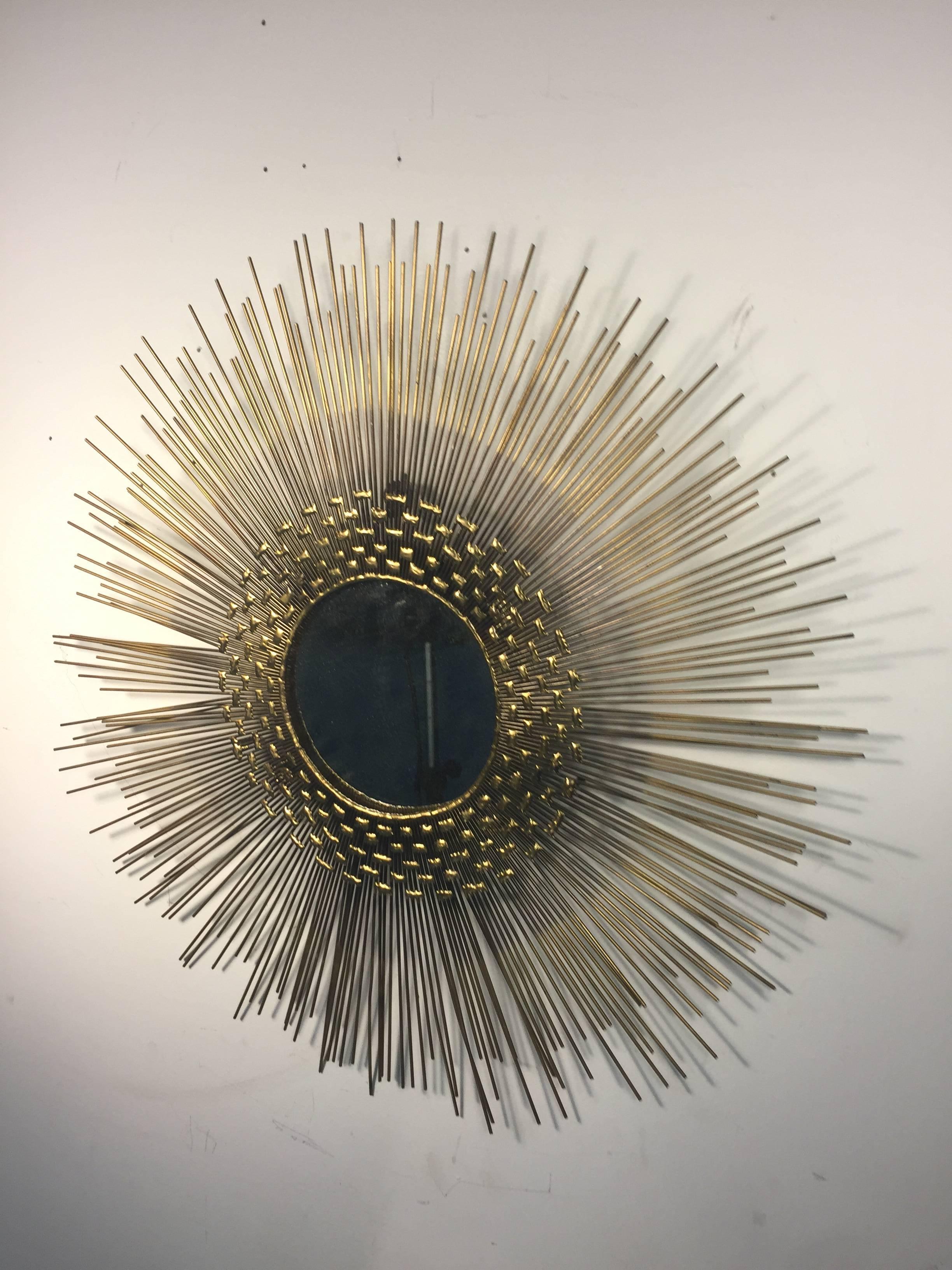 A stunning and dramatic sunburst wall-mirror by Curtis Jere with layers of thin radiating metal rods, circa 1970.