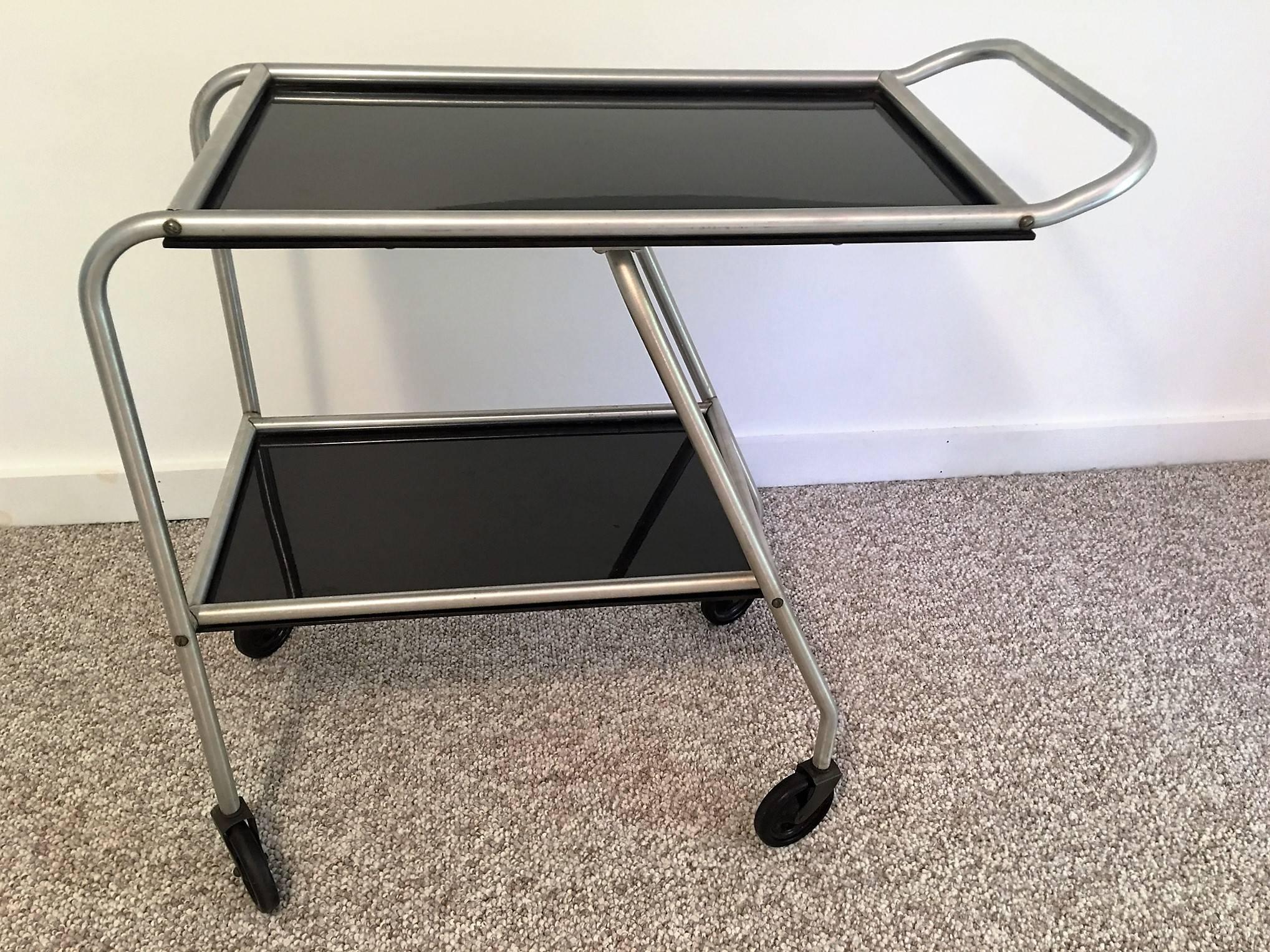 A great iconic bar cart designed in the 1930s called the aero art bar cart made by Frantz industries. Used in the 1930s on the DC-3 airplane by stewardesses serving cocktails. Composed of black bakelite and aluminum this aerodynamic cocktail cart is