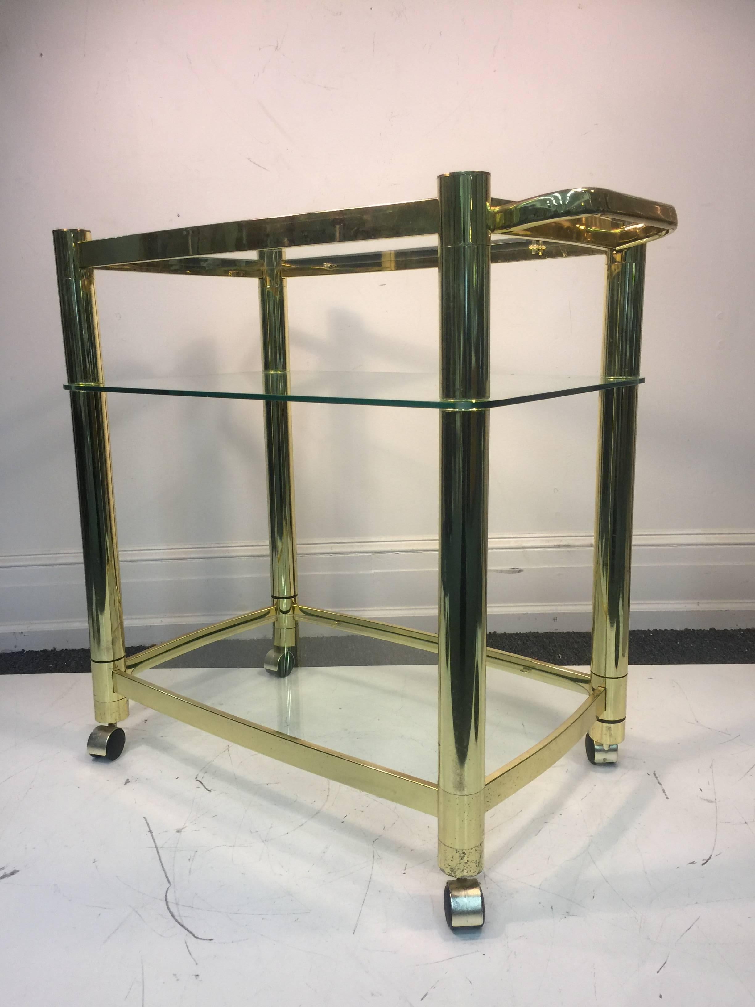 A terrific three-tier brass and glass tea cart in the manner of Milo Baughman, circa 1980. Good vintage condition with age appropriate wear.