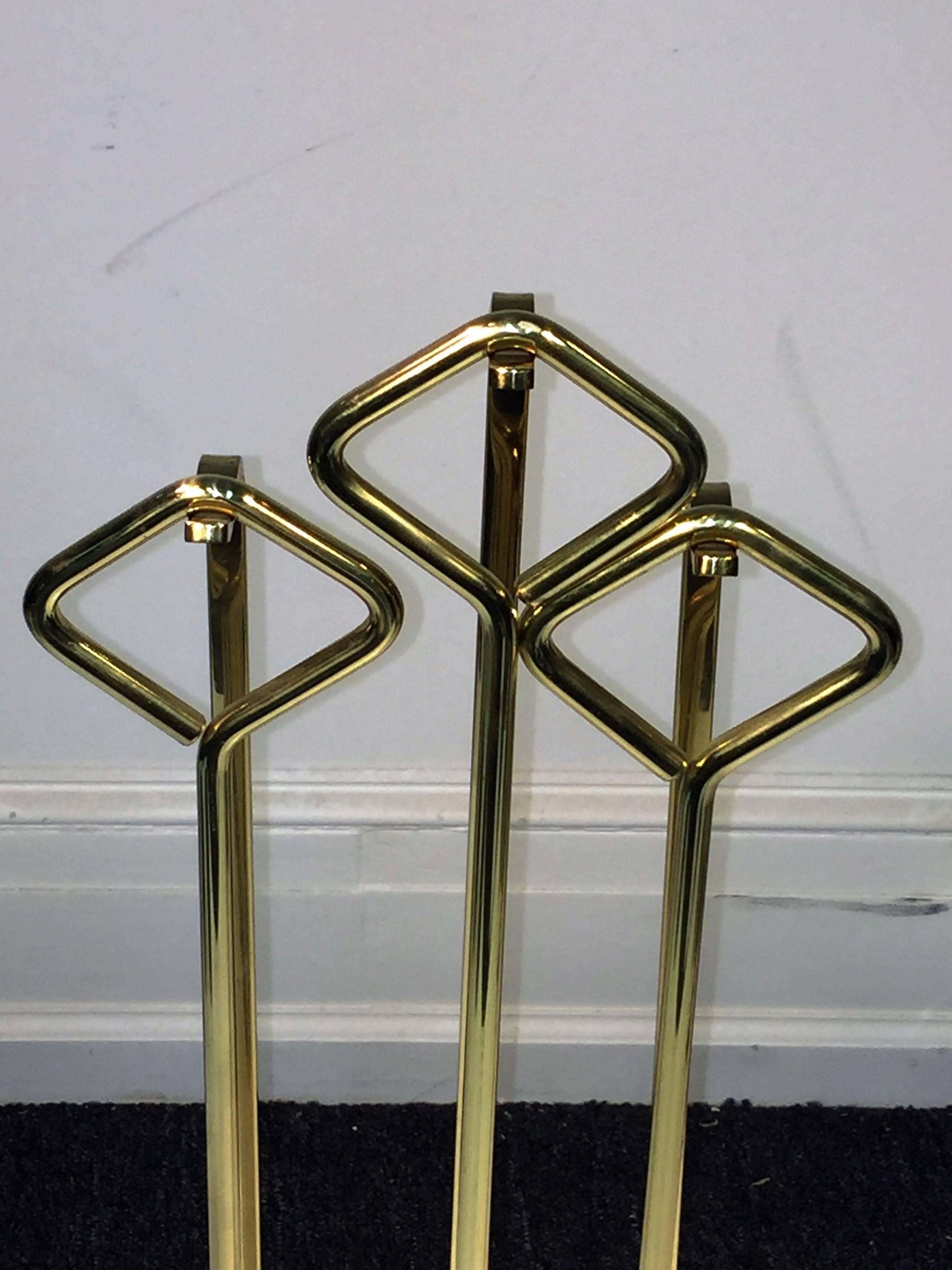Chic Italian set of three-tool firetools designed of goldtone metal and standing upon a thick rectangle glass base. With diamond shaped handles the poker, brush and shovel are very modern and sleek designed. The glass base measures at 9 1/2