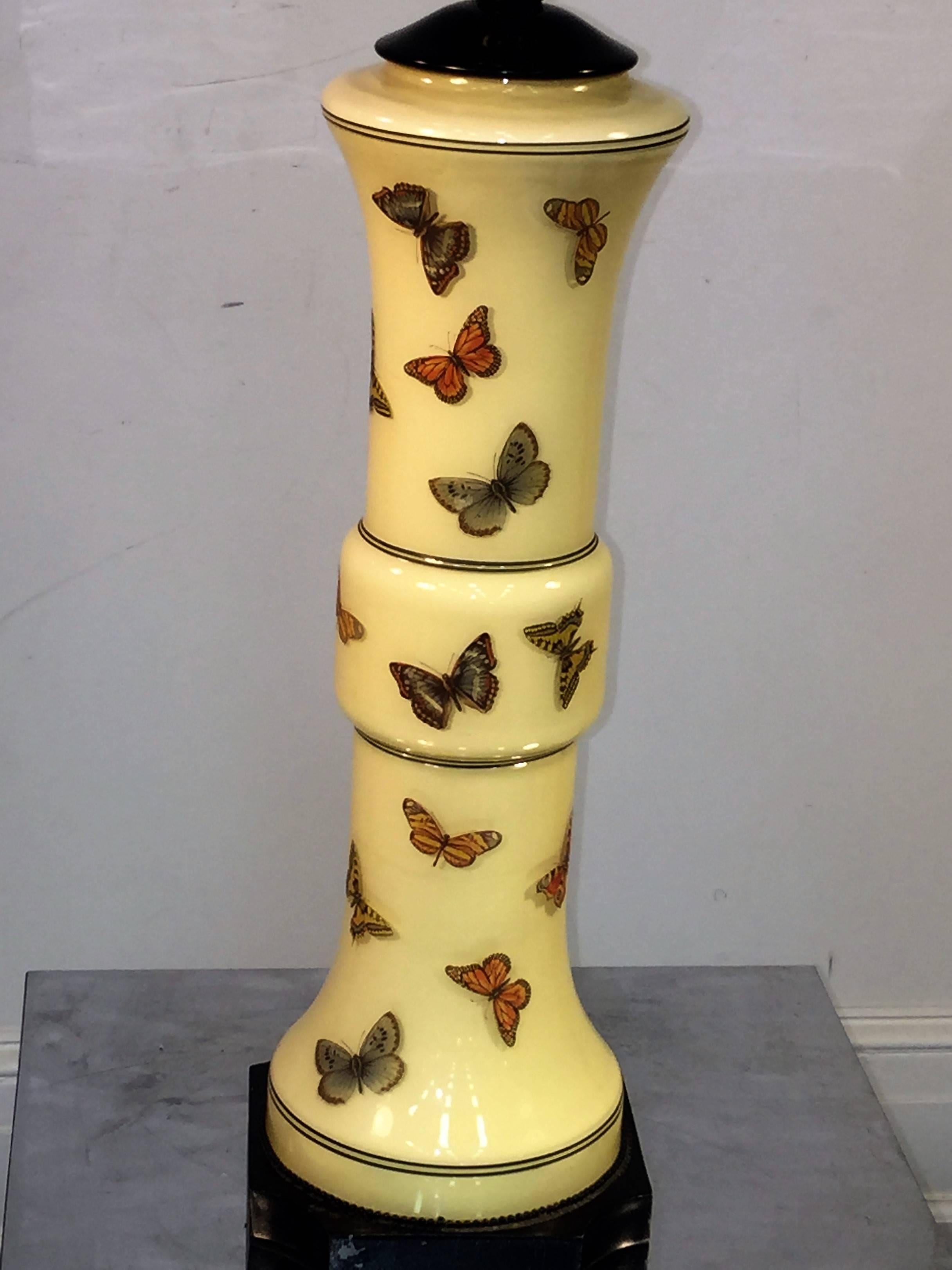 Pair of pale yellow glass lamps appliqued with colorful butterflies and black enameled line accents. Reminiscent of Piero Fornasetti's design. The height to the lamp fixture is 27