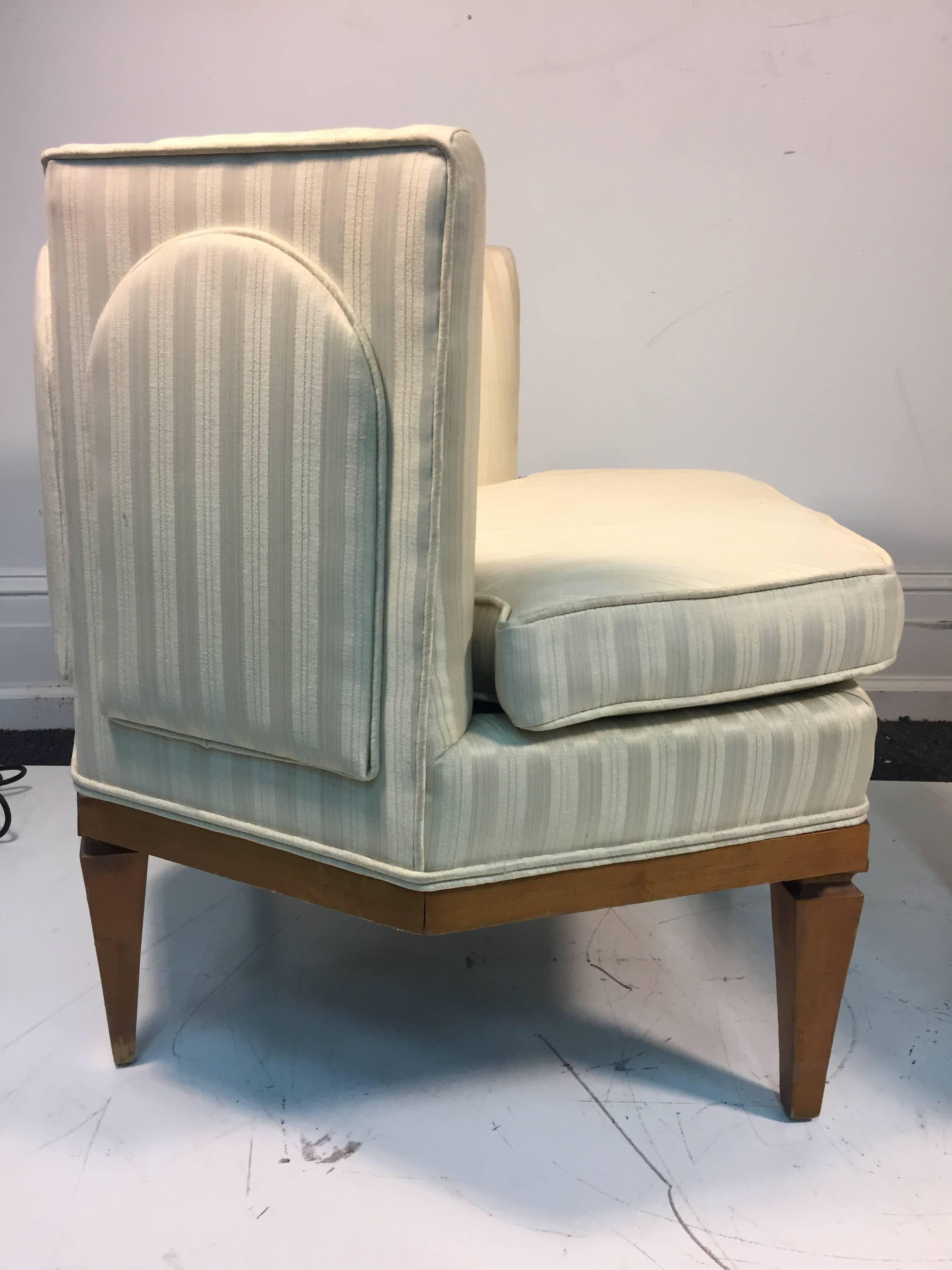 A rare pair of Hollywood Regency style club or slipper chairs in the manner of Tommi Parzinger. These chairs have an unusual design and are upholstered in their original striped satin fabric, circa 1960.