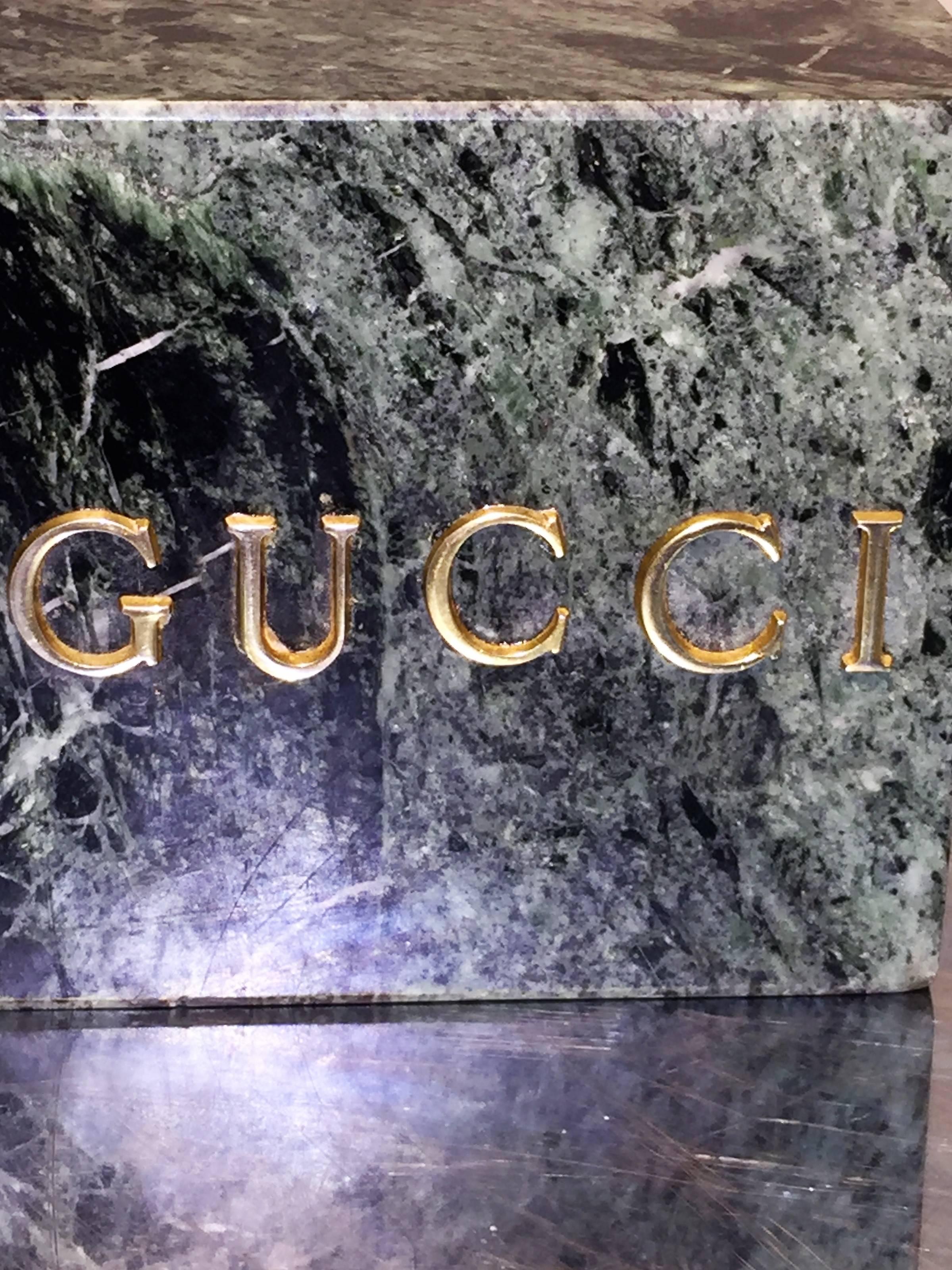 Substantial marble bookends with gilded brass Gucci nameplates. These would be great on a high end modernist desk holding your books of choice or as chic sculptures.