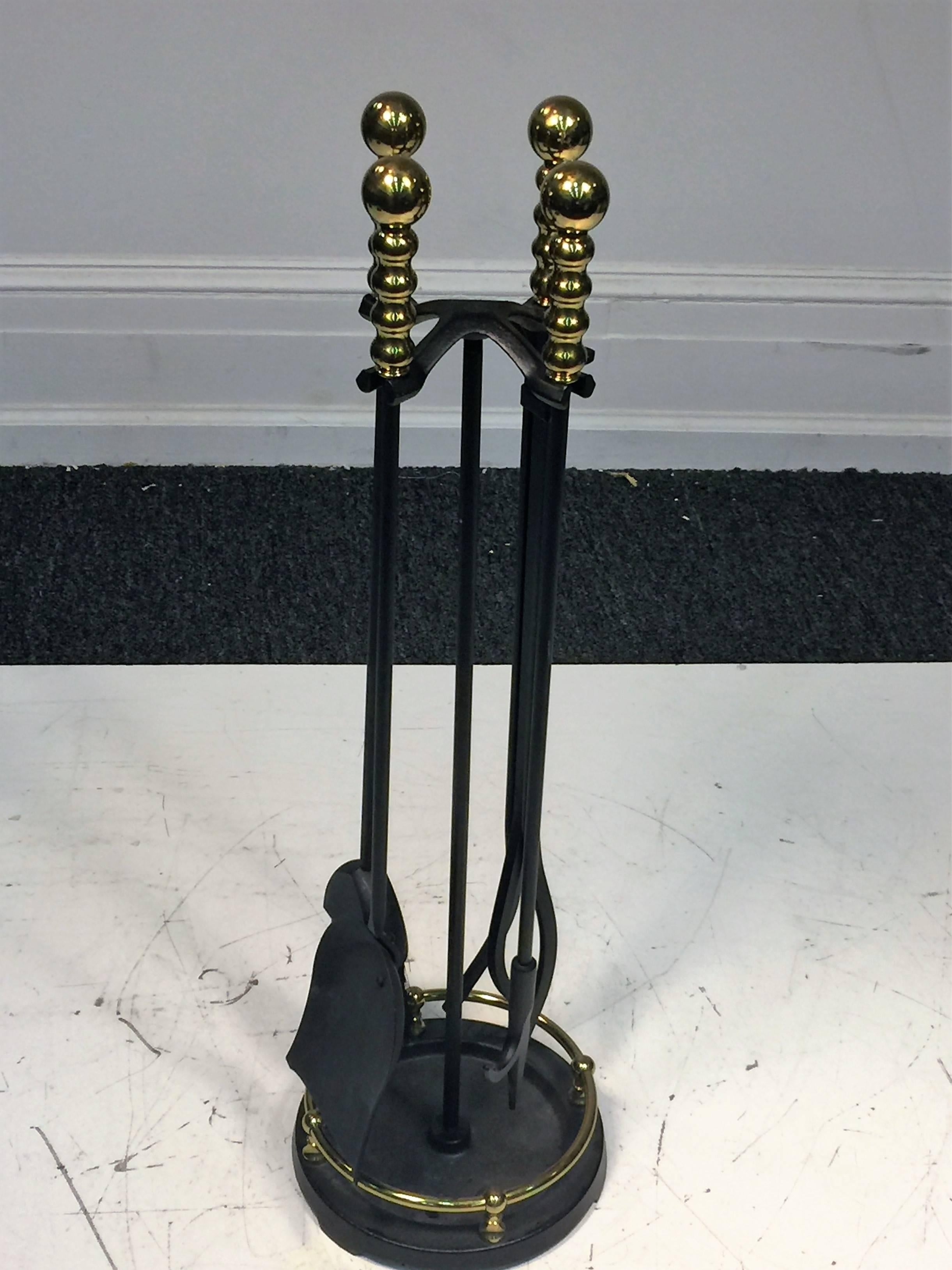 Great four piece fire tool set with brass ball handles and black enamel iron stand. Decorated with a brass gallery on the black iron round base. Each fire tool measures at 28