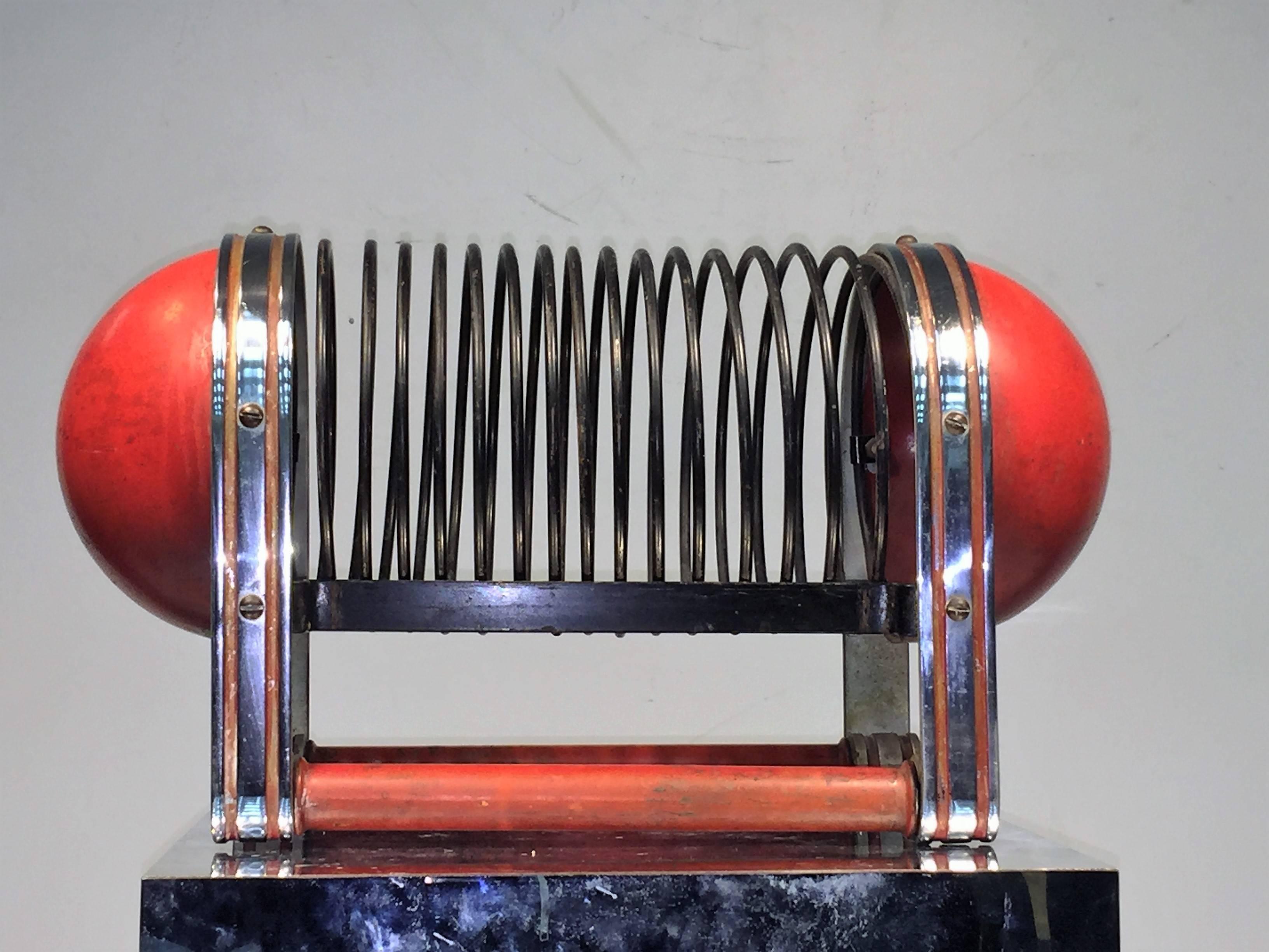 Incredible original red modernist black and chrome coil form magazine rack designed in 1929. Both an Interesting sculpture as well as a functional magazine holder this is really an unusual piece.