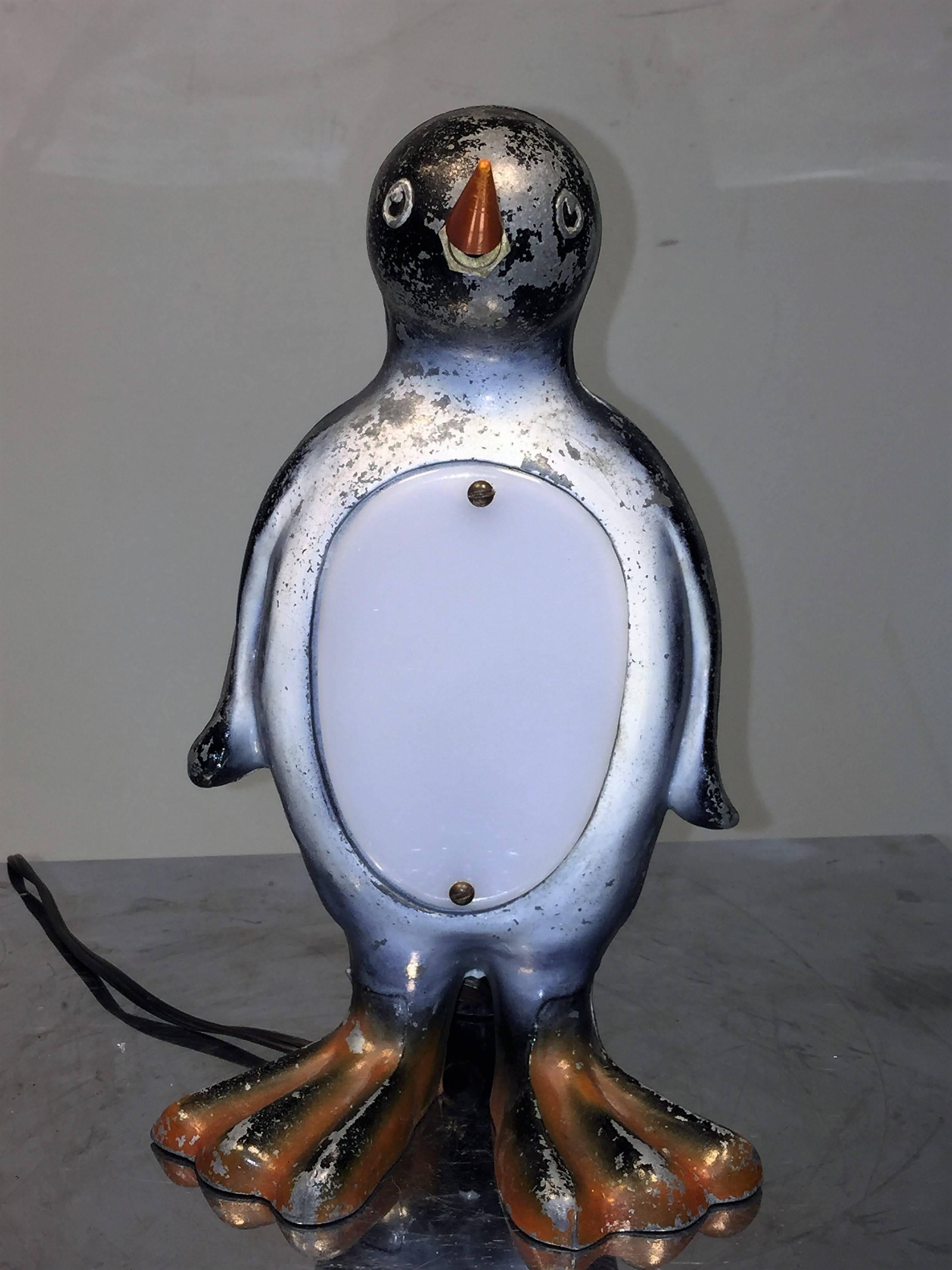 Ingenious design cast polychromed black and white metal penguin lamp with white Lucite chest and orange bakelite beak on/off switch. Created in the 1930s this great accent lamp would be a soothing night light on your bedroom nightstand. To change