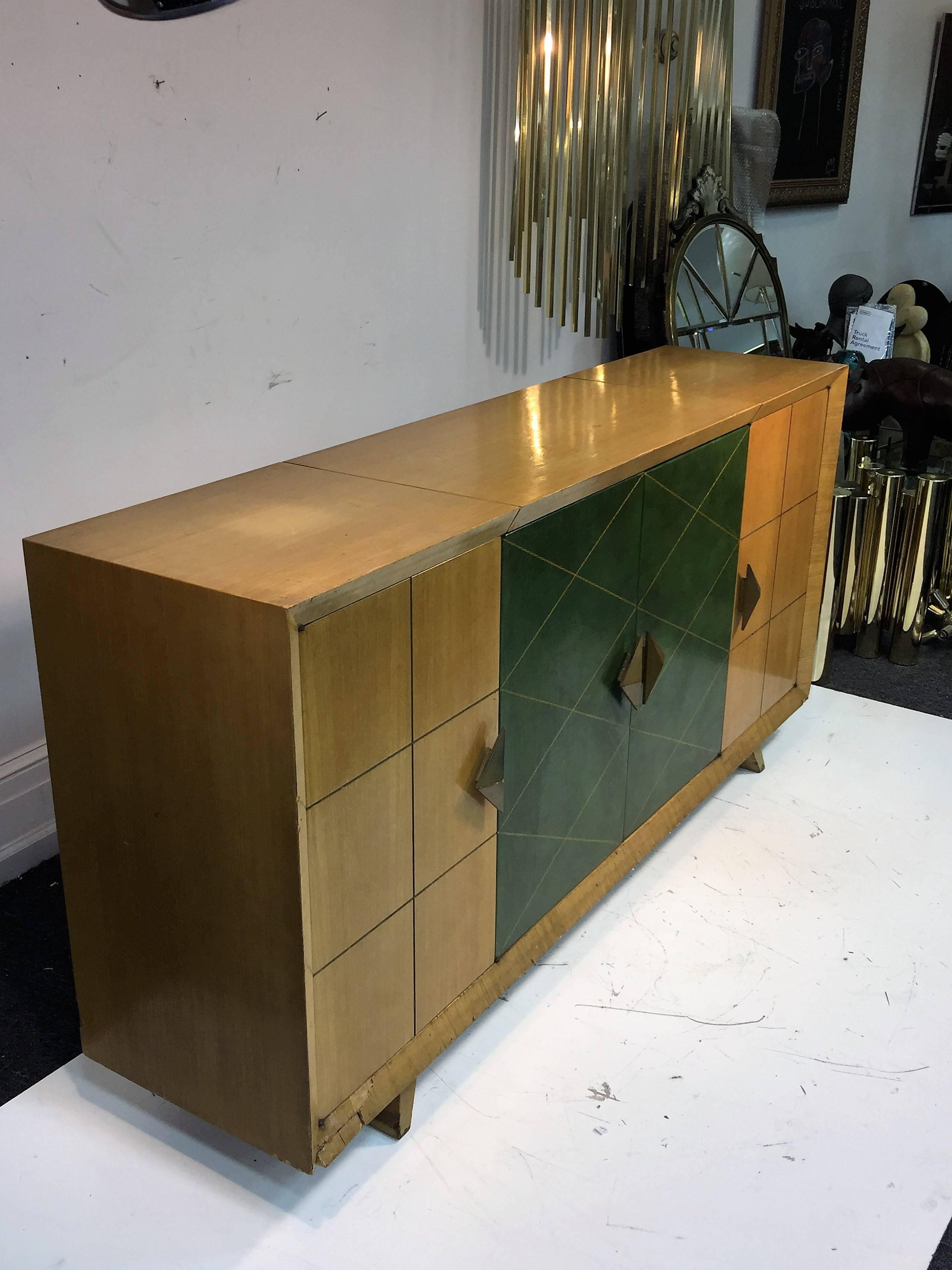 Great design bleached mahogany veneer bar cabinet designed by Tommi Parzinger with center doors covered in emerald green leather with gold embossed diamond pattern. Moderne gold triangular faceted wood handles that compliment the diamond design in
