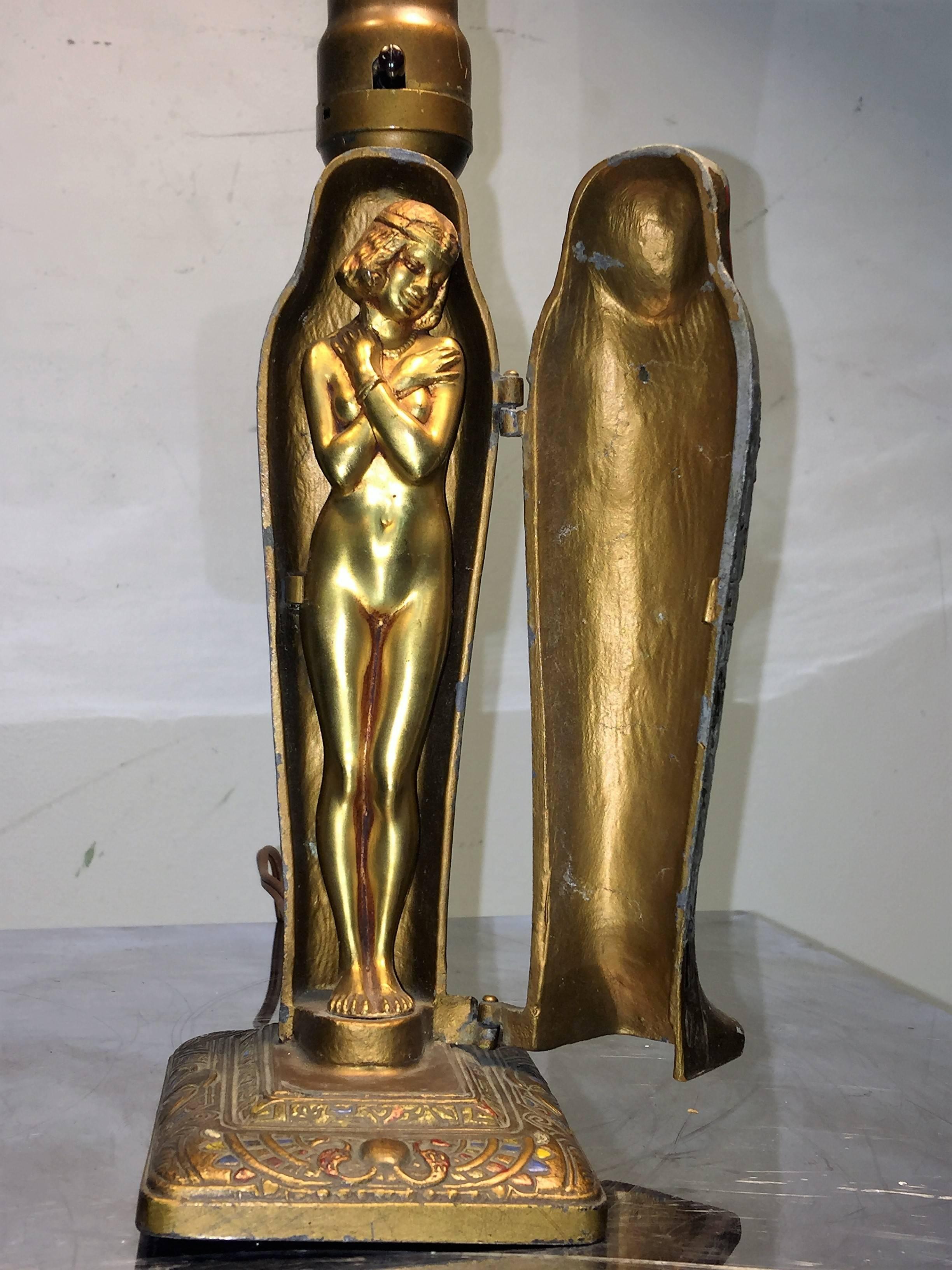 Great cold enamel metal colorfully decorated sarcophagus that opens on hinges to reveal a gilded nude female wearing an Egyptian headdress. You can use this 1923 naughty nude lamp as an accent lamp. Created by Louis V Aronson in 1923, who is the
