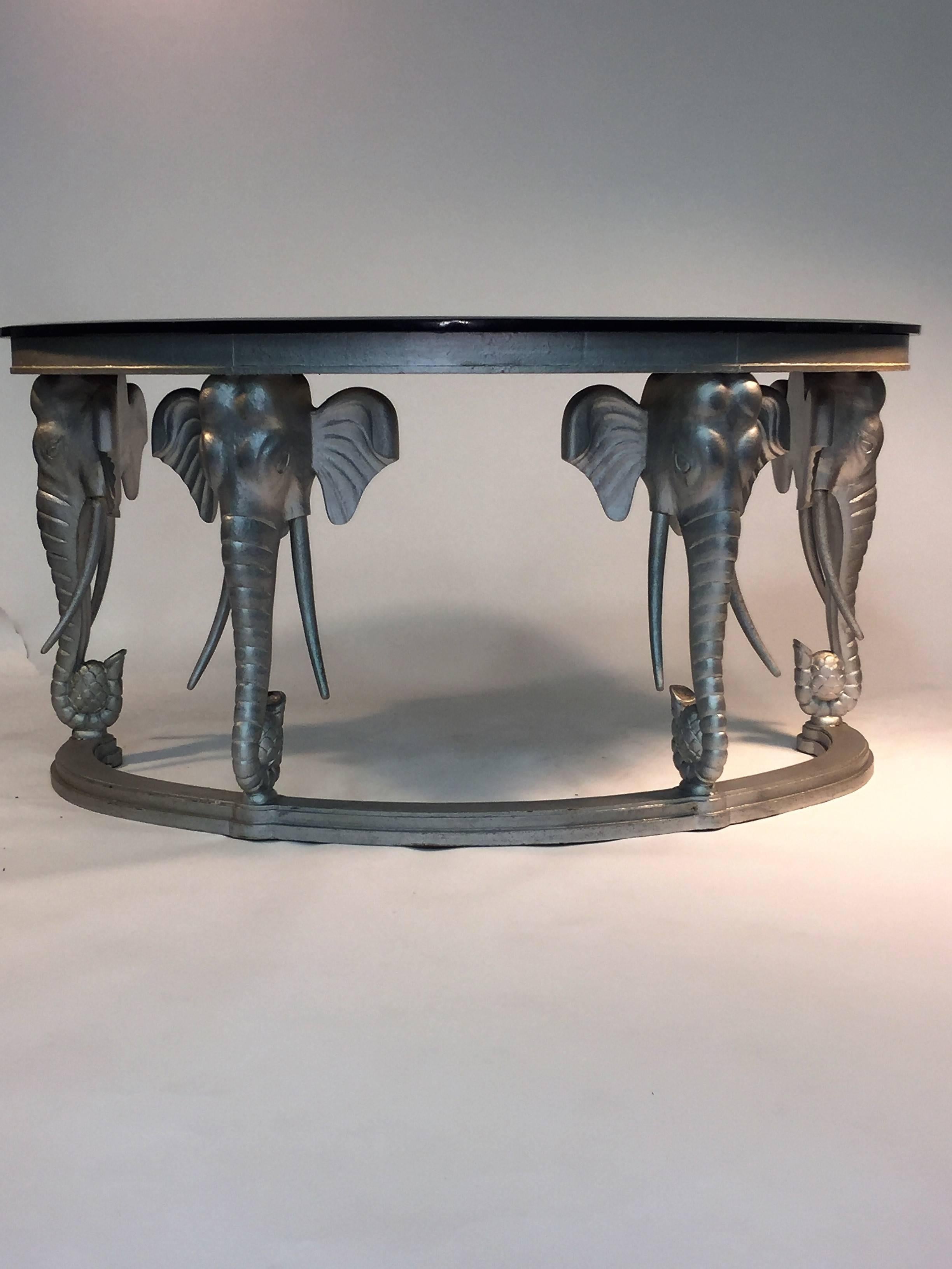 Beautiful hand-carved wood console table or desk designed in the 1970s depicting four full elephant heads with beautiful tusks holding a pineapple in their trunks. Perfect for an entry way with a glamorous mirror above it or as a desk for your