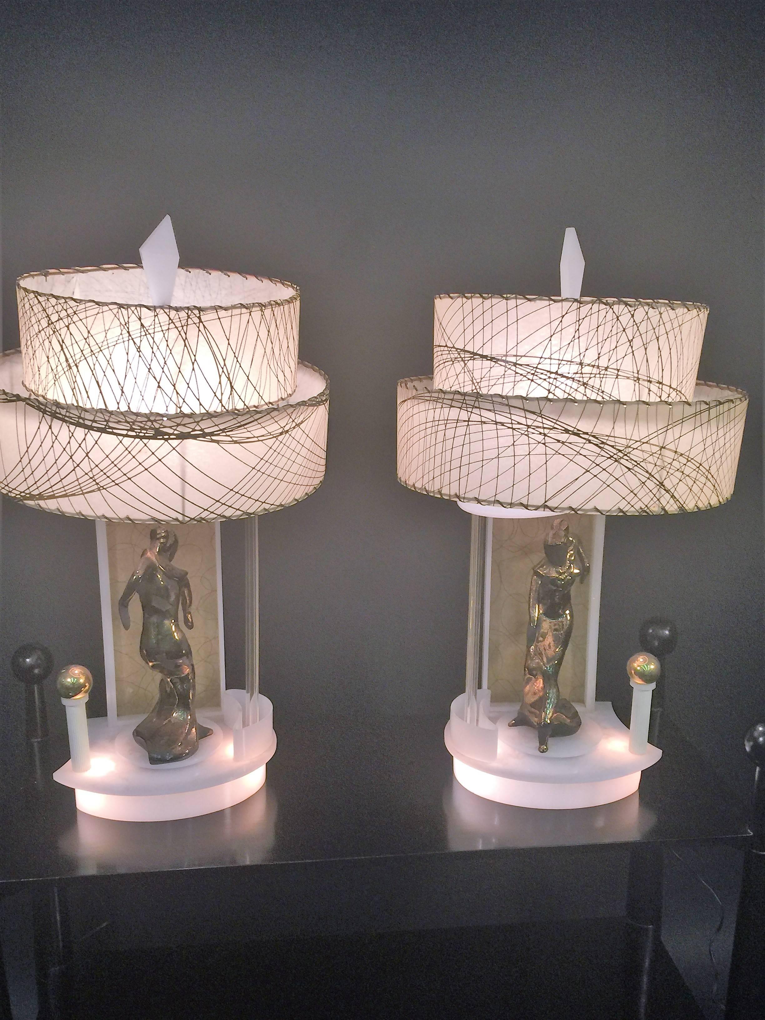 These really cool lamps are made of white Lucite and clear Lucite rods. The gold swirled parchment paper background are the backdrop for the metallic bronze, glossy and flat black glazed ceramic dancers. These lamps have motorized bases for the
