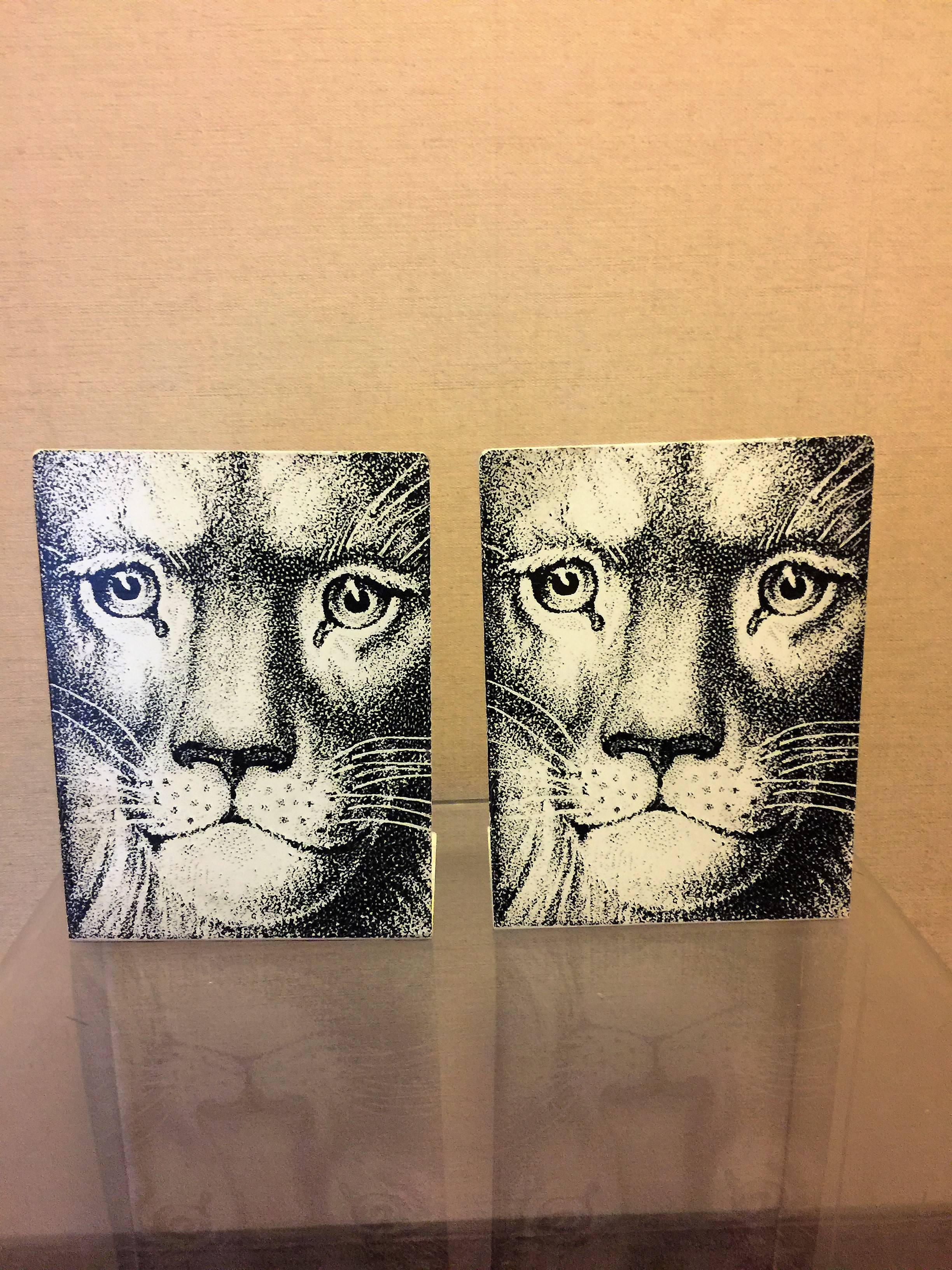 Dramatic pair of lion face black and white lithographed metal bookends by Italian visual master Piero Fornasetti.