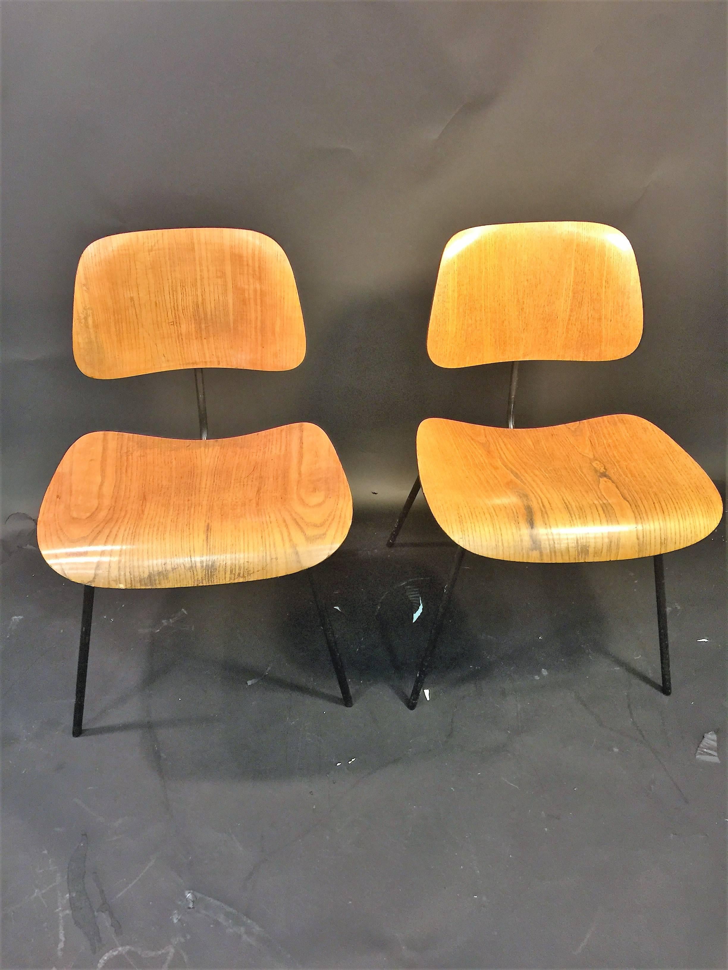 Pair of Mid-Century wood and black iron dining chairs designed by Charles Eames Made By Herman Miller in the 1950s. In original condition with some veneer chips as shown in photos.