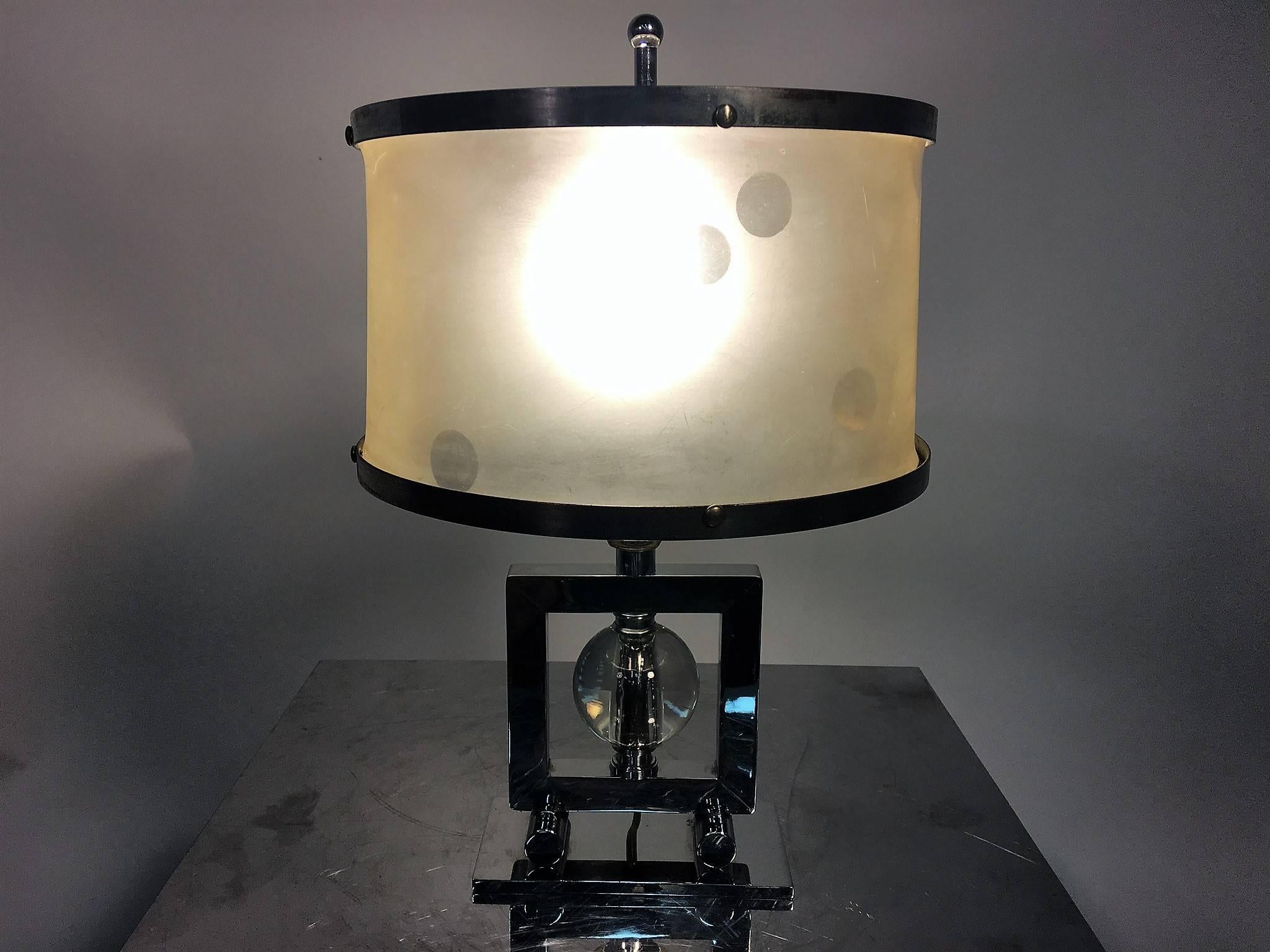 Beautiful chromium on brass geometric design Art Deco lamp with glass ball in center in a square tubular frame resting on Tootsie roll feet on a rectangular base. Retaining the dotted translucent white vellum shade trimmed with chrome trim and great