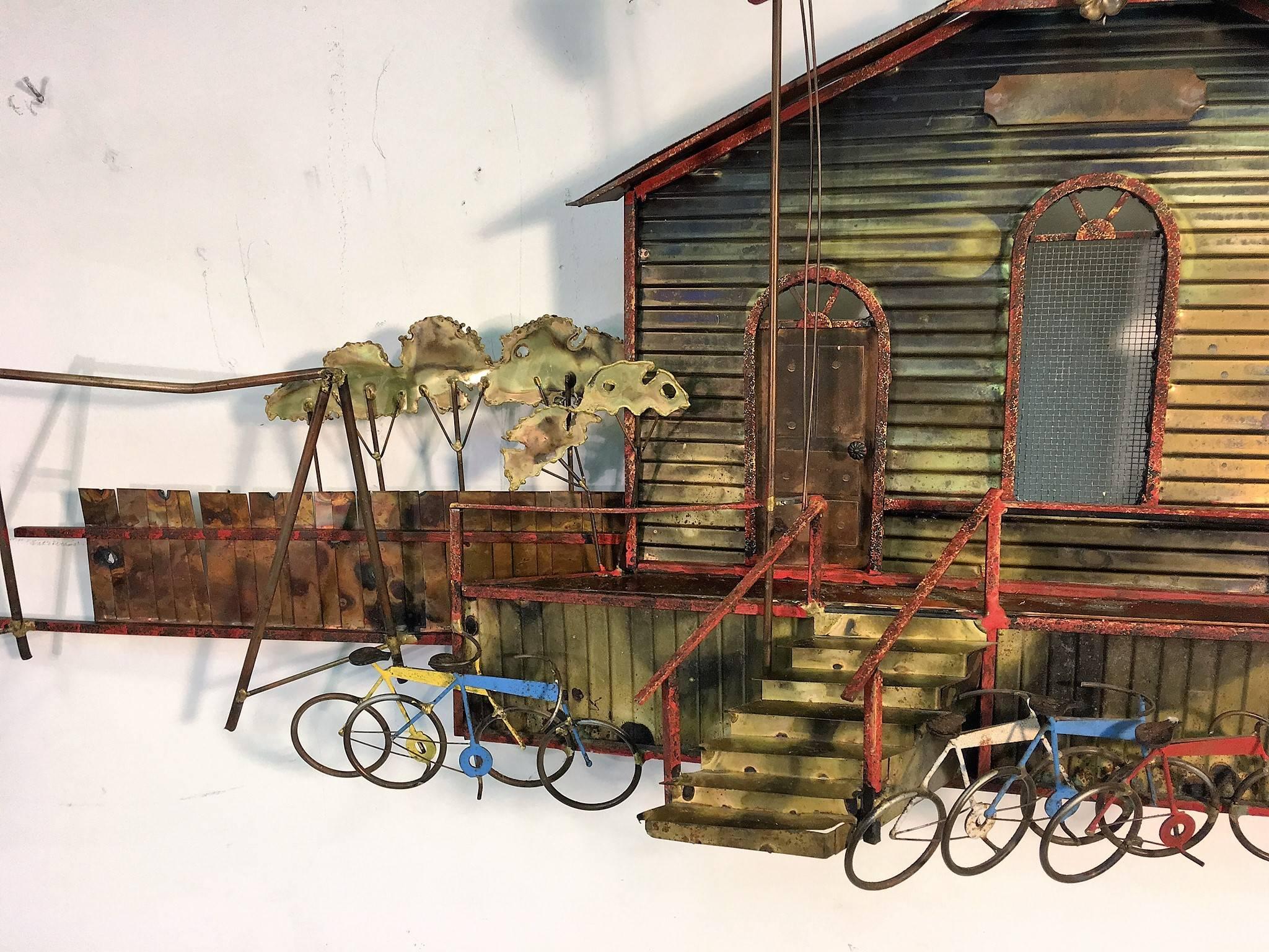 Intricate mixed metal and materials enameled and torch cut schoolhouse with American flag on pole and ringing school bell. Great detail with blue, yellow and red bicycles in front on both sides of the stairway. Pair of red picnic tables, fence and