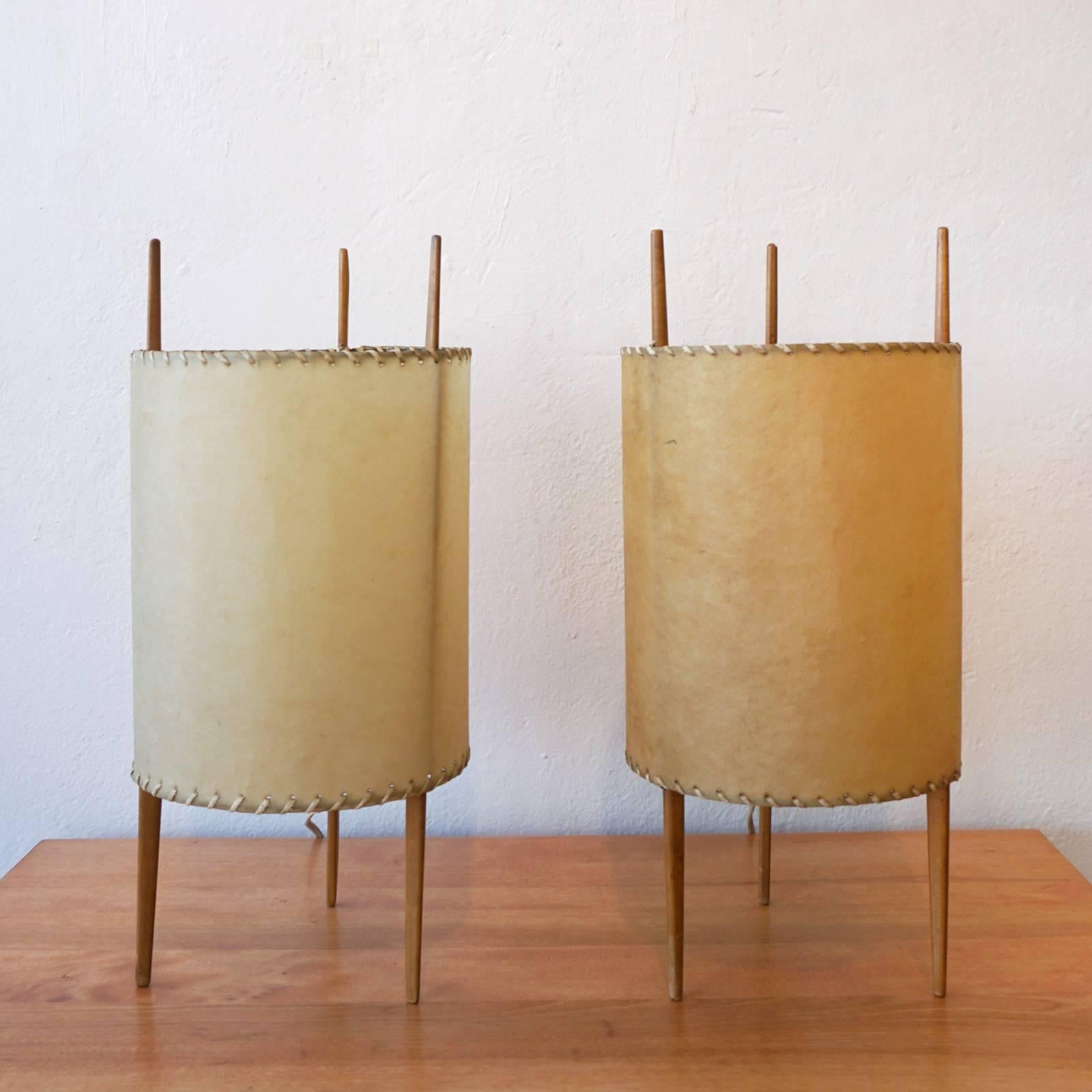 A pair of three-legged table lamps, designed in the 1940s by Isamu Noguchi for Knoll. This variation has laced fiberglass parchment shades and tapered cherry legs.