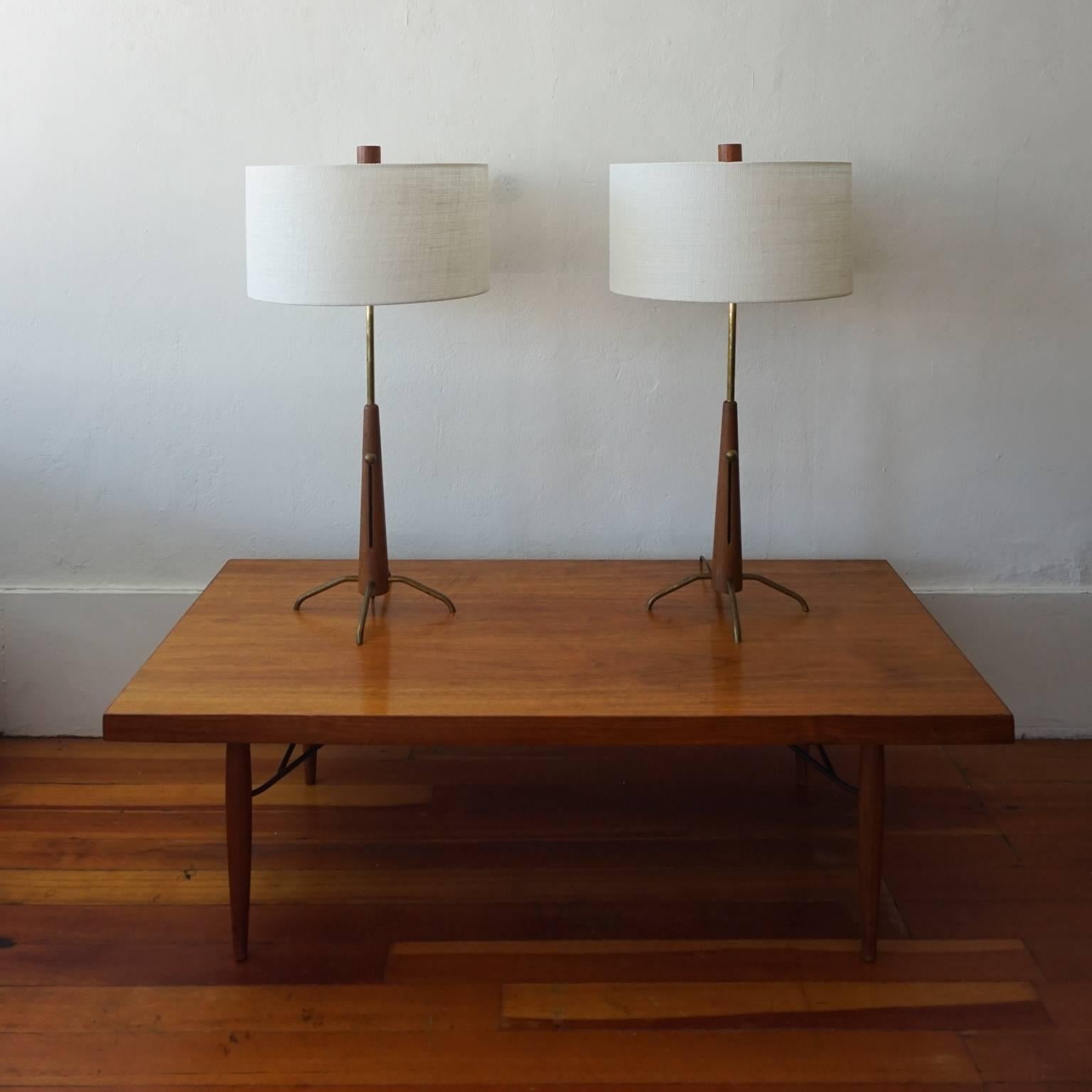 Pair of 1950s walnut and solid brass table lamps designed by Gerald Thurston for Lightolier. Solid brass balls unscrew to allow for sliding height adjustment. New shades and walnut finials. 

Measures: Height adjusts from 24
