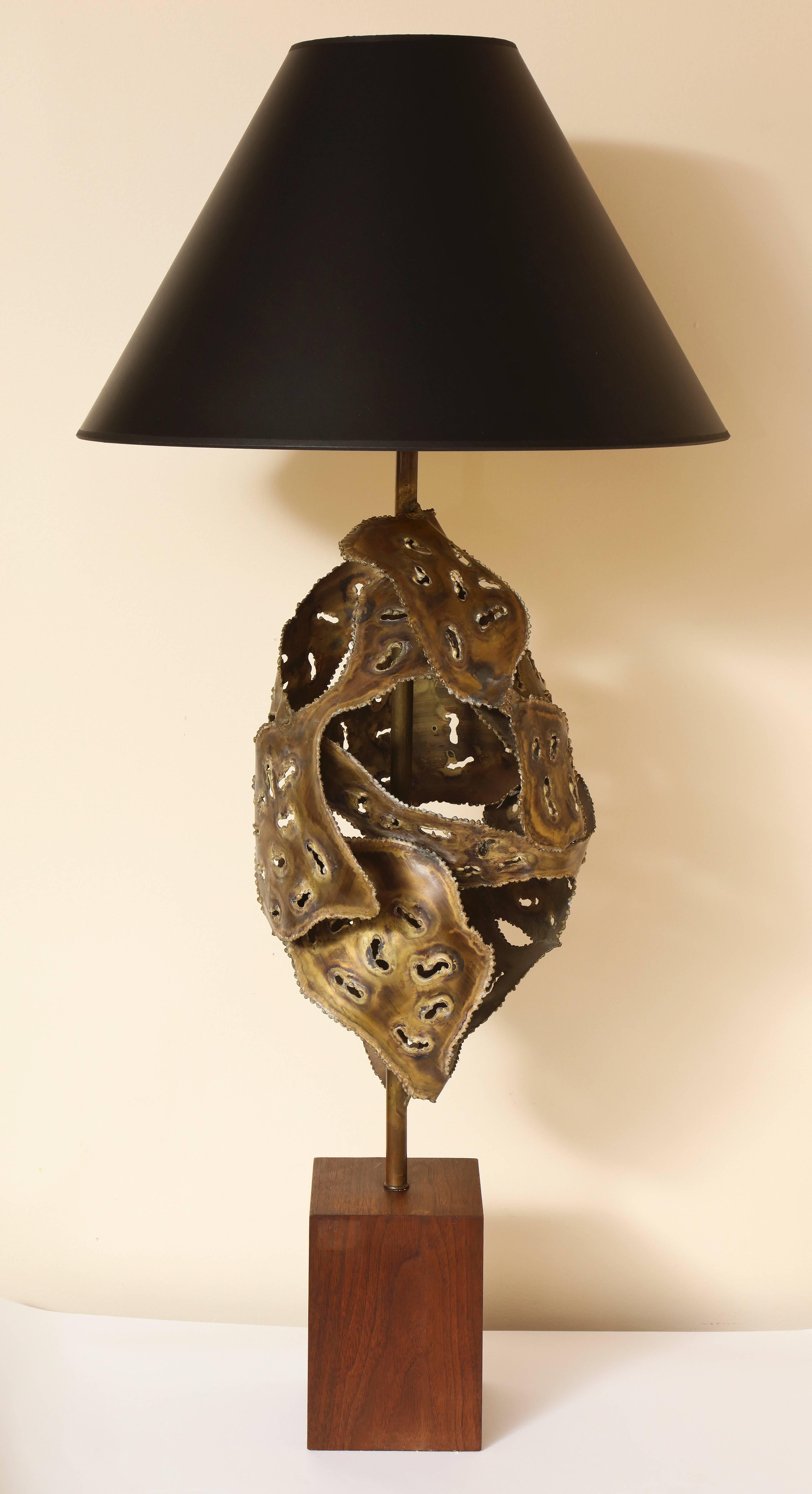 A dramatic and unique sculptural Brutalist welded metal table lamp with pierced design, supported on a wood plinth base. 

Dimensions: 40