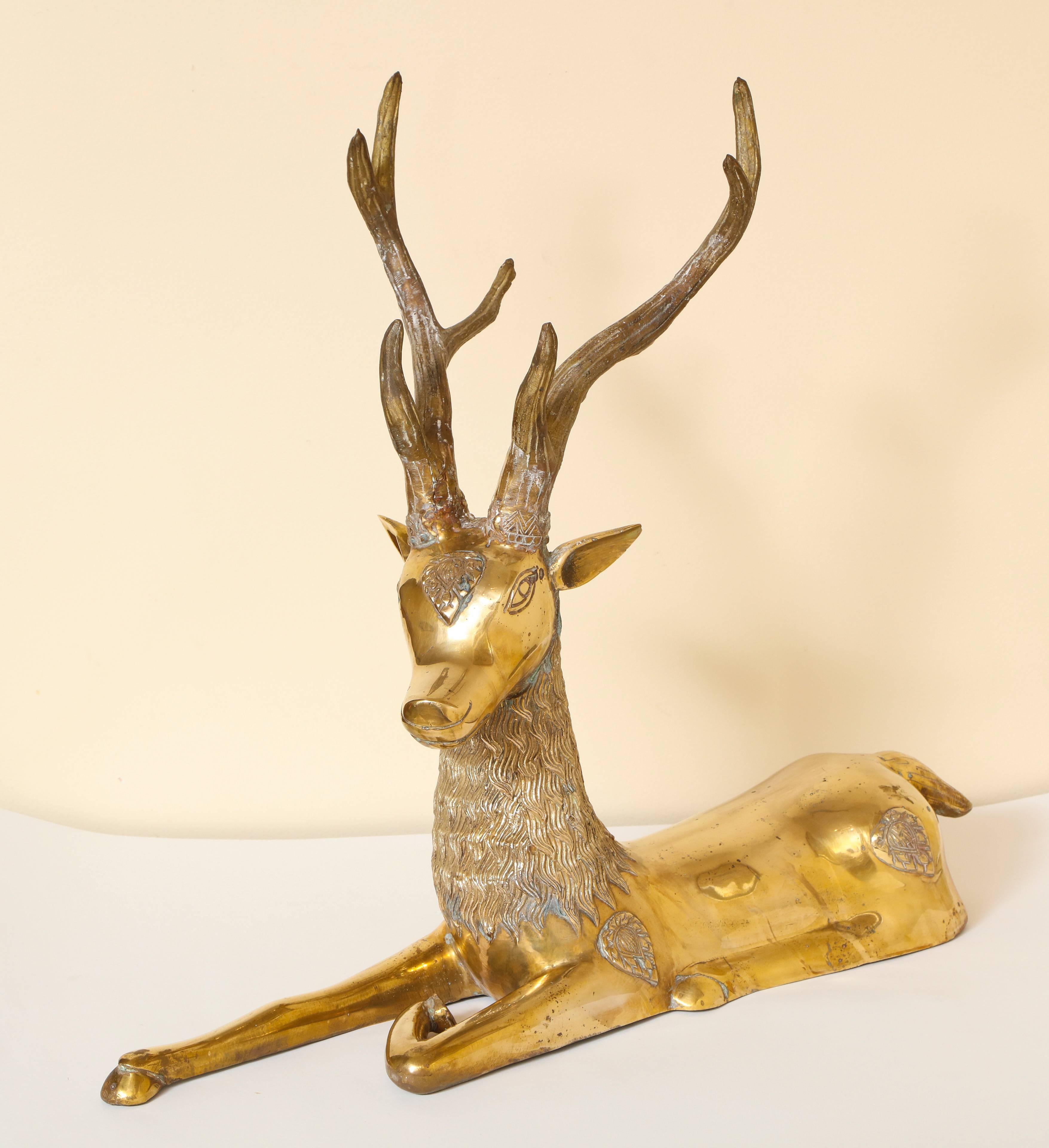 Pair of dramatic and large seated 1970s brass deer with fanciful decoration by Sarreid Ltd. 
Dimensions: 20