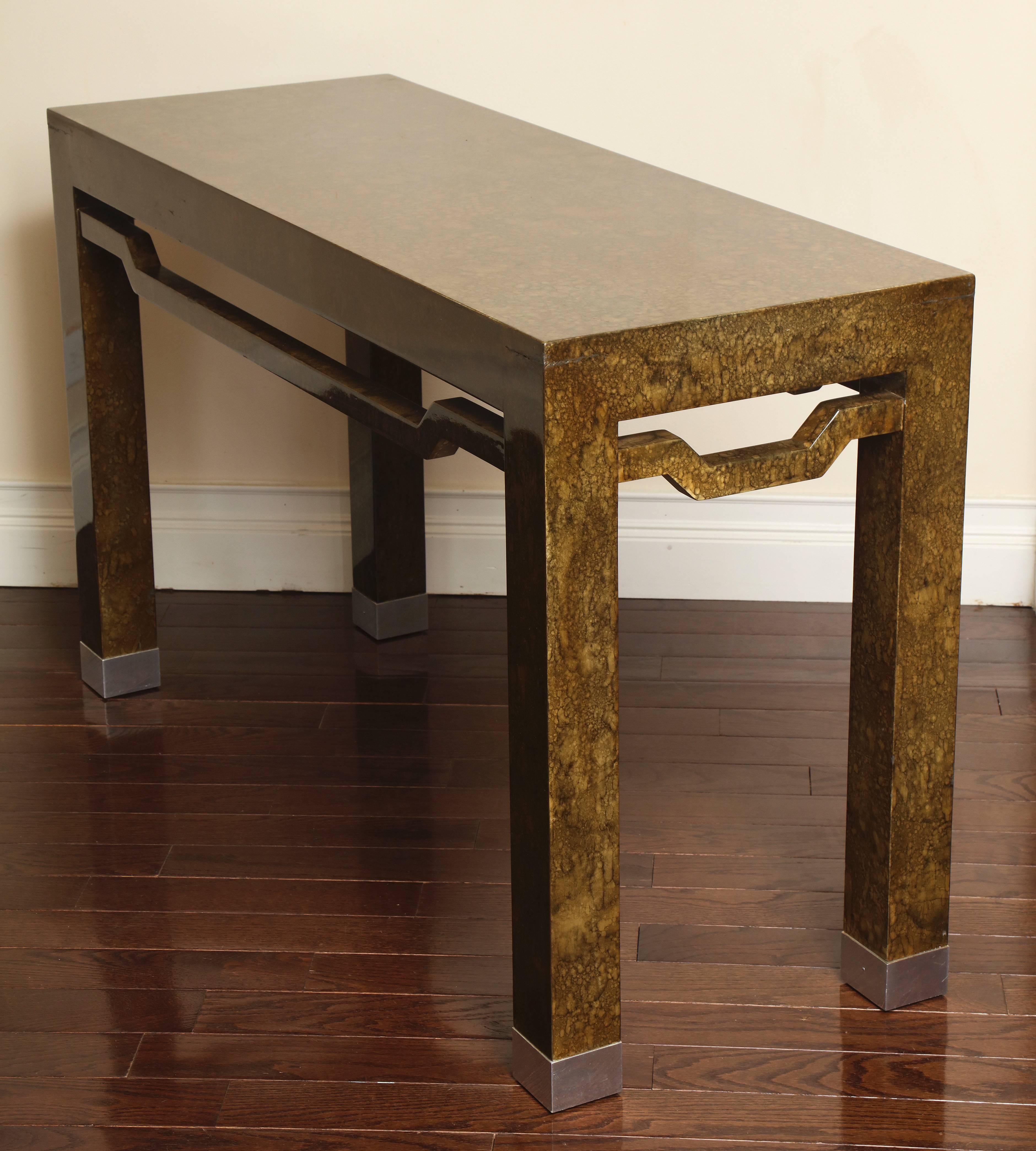An Asian inspired lacquered console table with chrome feet and open apron motif.
   