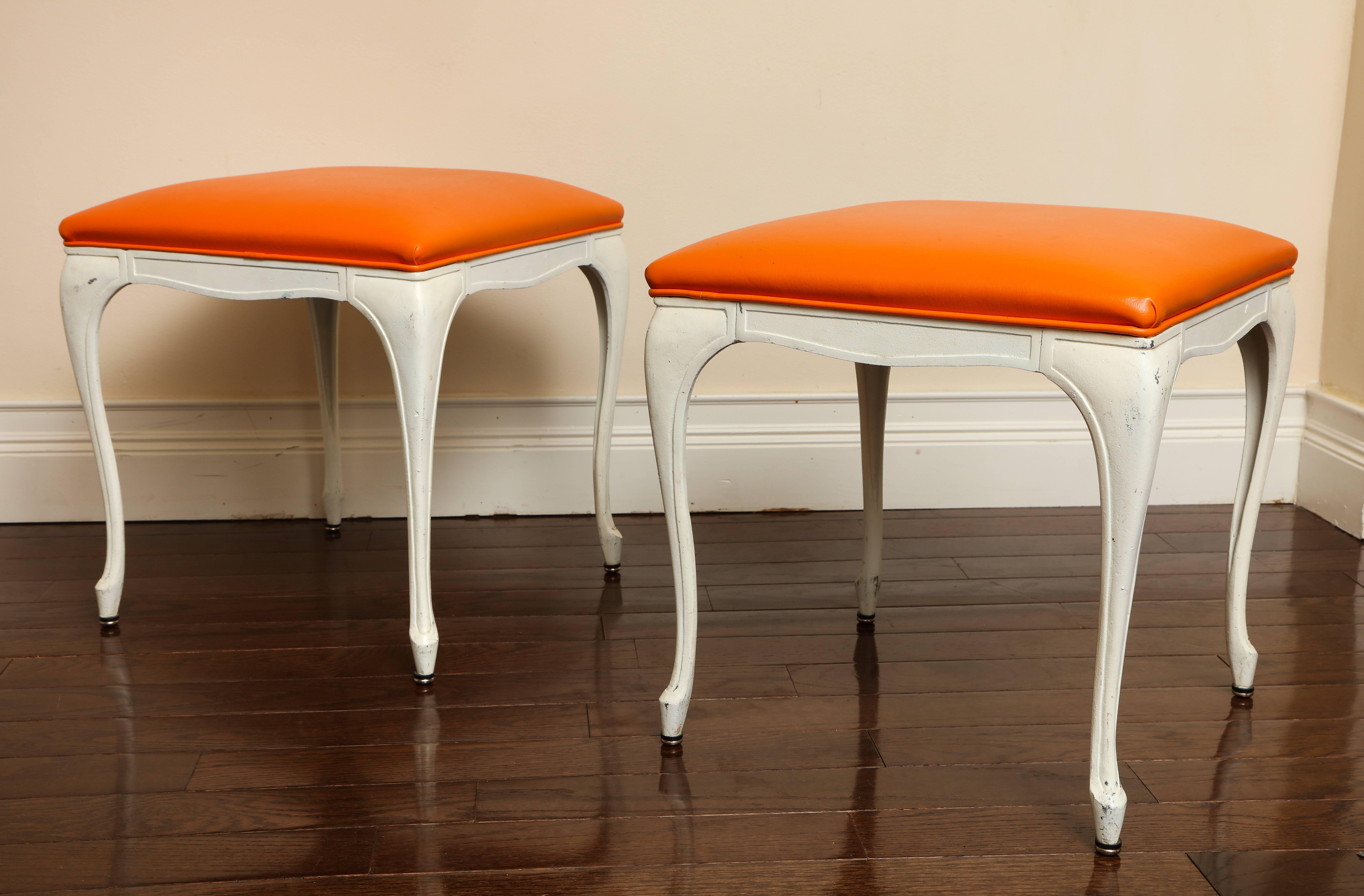 A pair of Mid-Century Modern painted white metal benches or stools with elegantly shaped apron, cabriole legs; the seat cushions upholstered in vibrant orange leather.
Size: 16 1/2