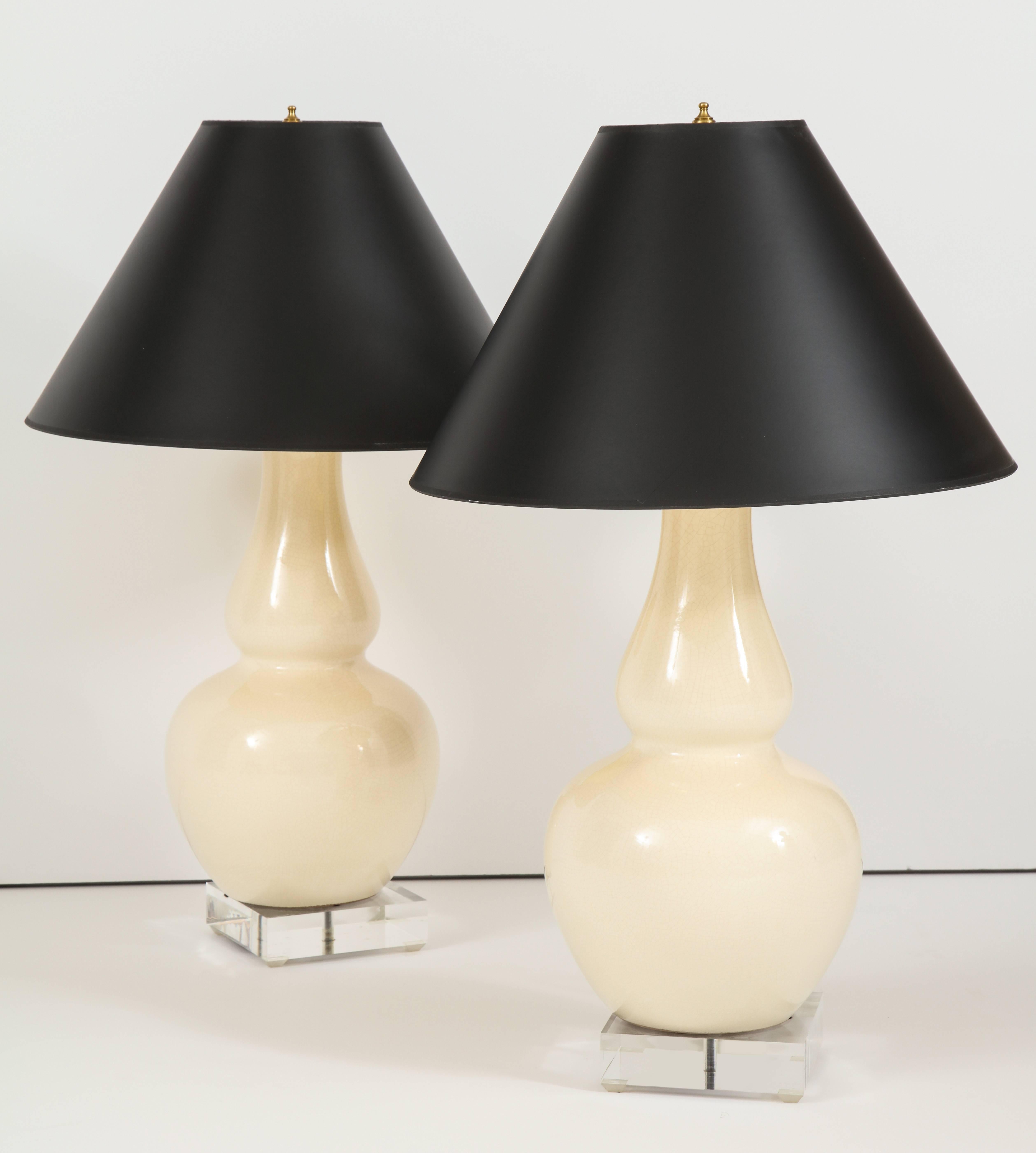 An Italian pair of cream crackle glazed lamps in double gourd vase form; supported on square Lucite bases, 
Italy, circa 1960
Size: 19" high x 5" square base.