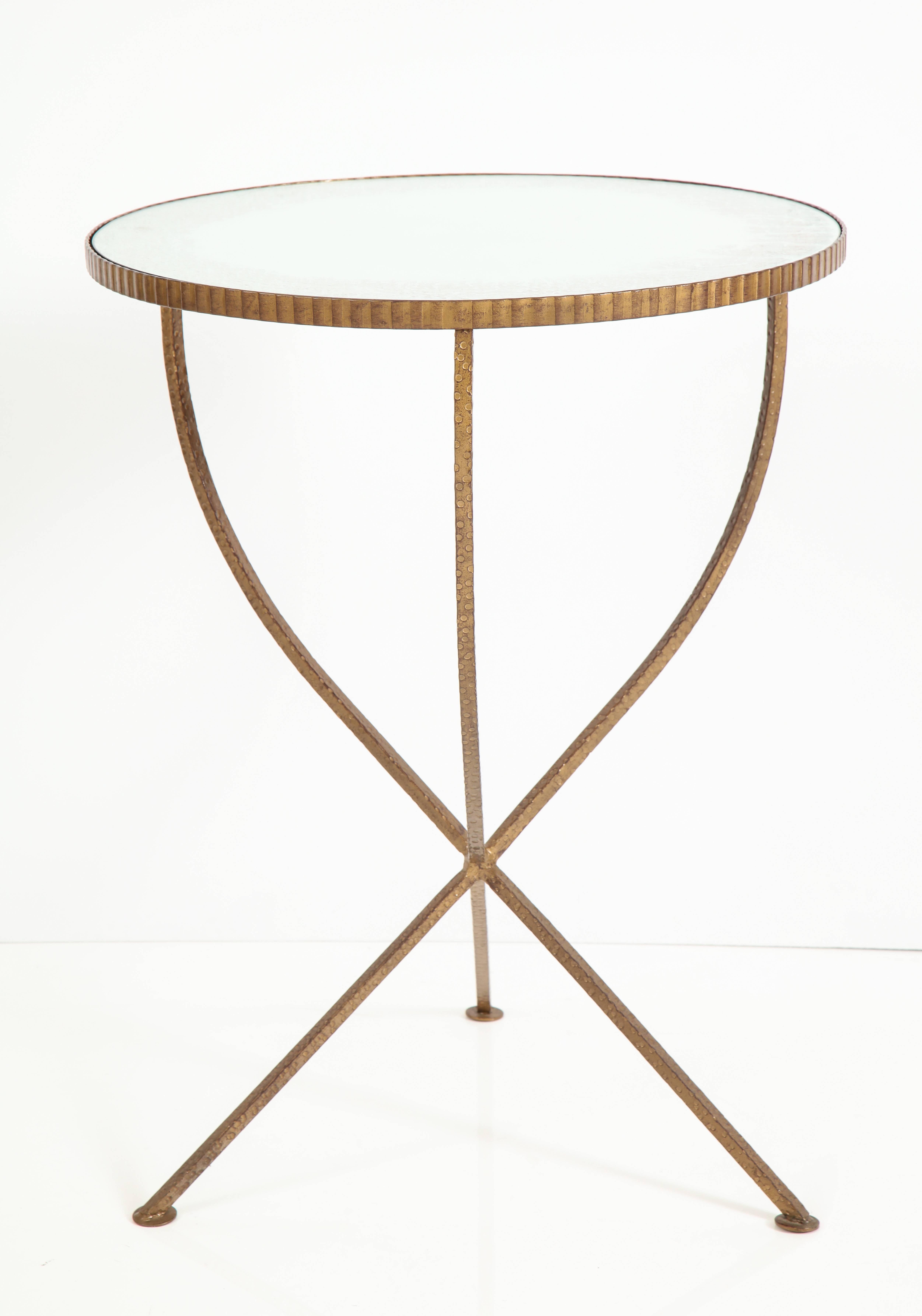 An Italian Art Deco hammered bronze gueridon with tripod base and mirrored glass circular top, the top with ribbed apron; the glass antique with hints of red along the edges.
Italy, circa 1940
Size: 27 3/4" high x 21"