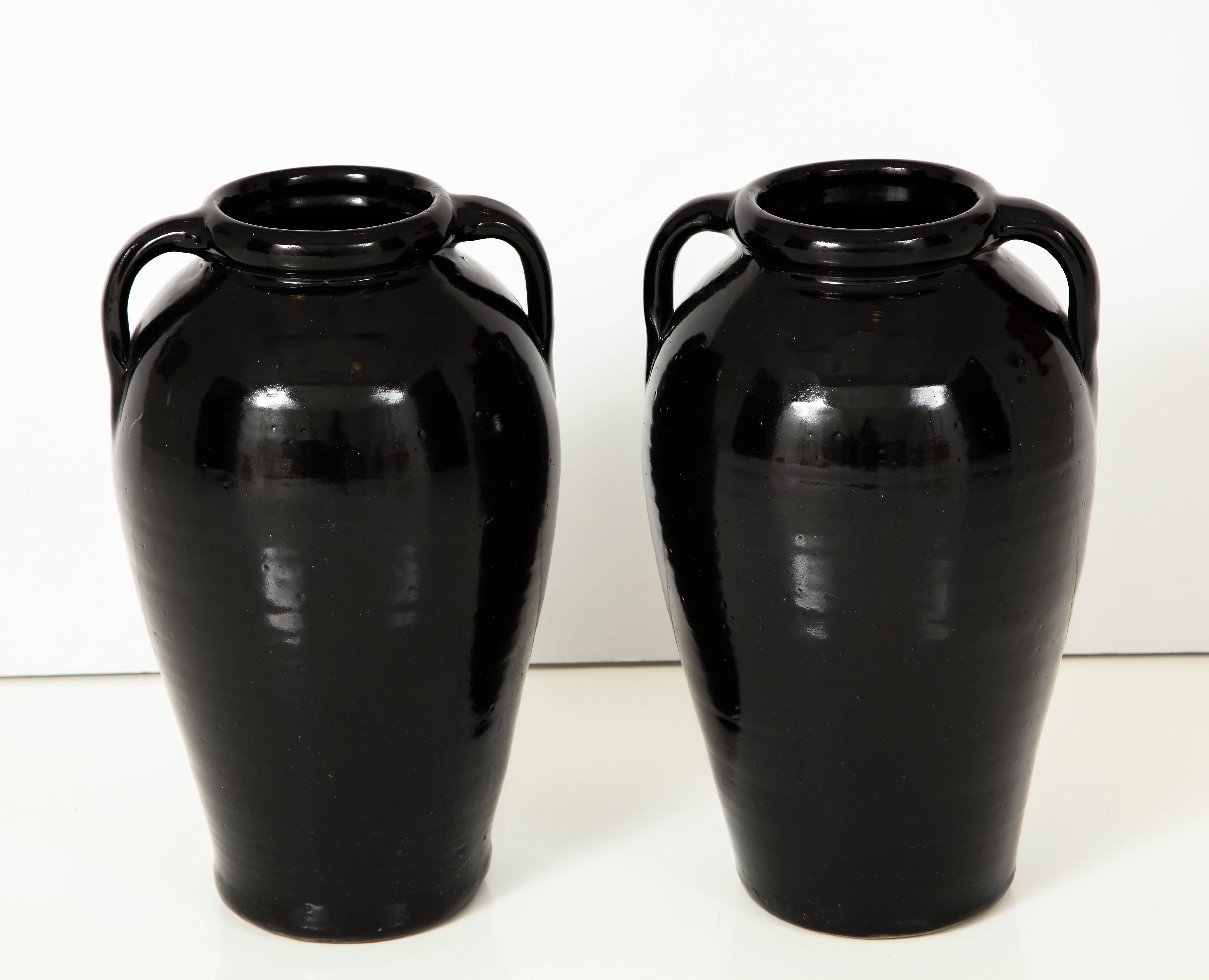 A grand scale and striking pair of black glazed stone ware vases or jars with handles; of very heavy weight. 
American, mid-20th century 
Size: 18 1/2