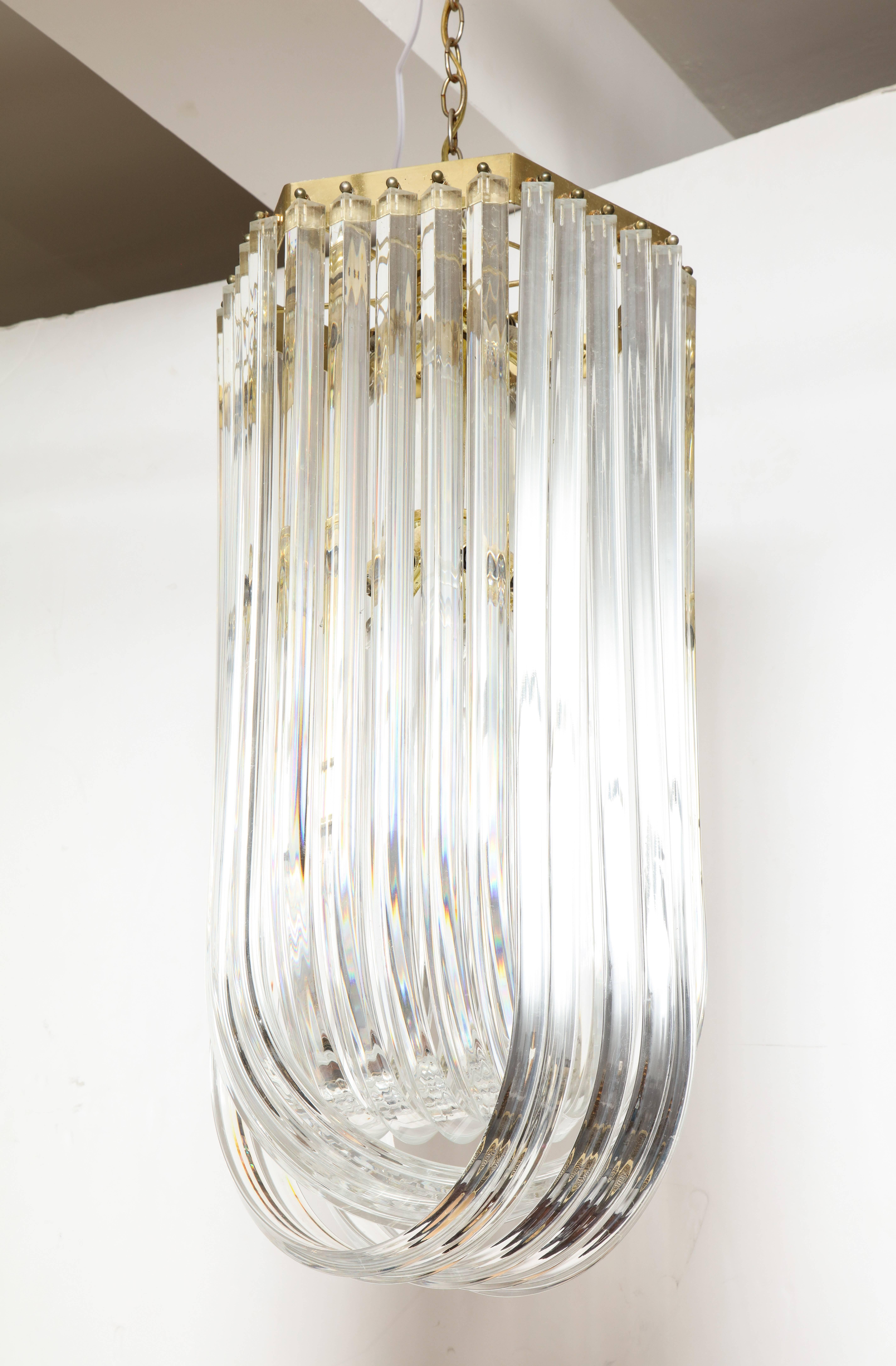 A large and dramatic vertical hanging Lucite ribbon design chandelier with brass fittings. 
American, 1960s.
Size: : 32