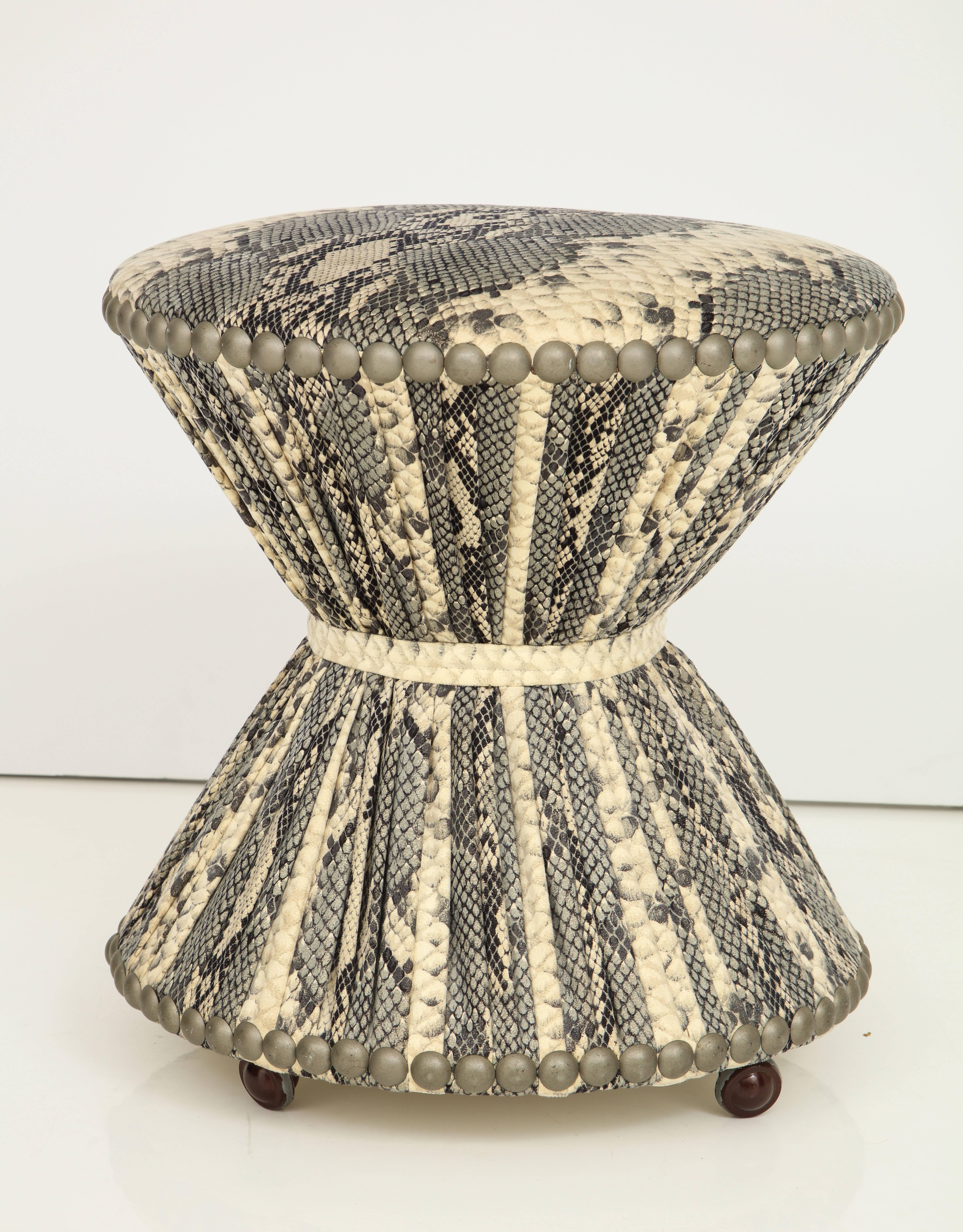 A chic snakeskin print fabric stool with corseted form on casters and with studded trim decoration. 
American, 1970s .
Size: 18