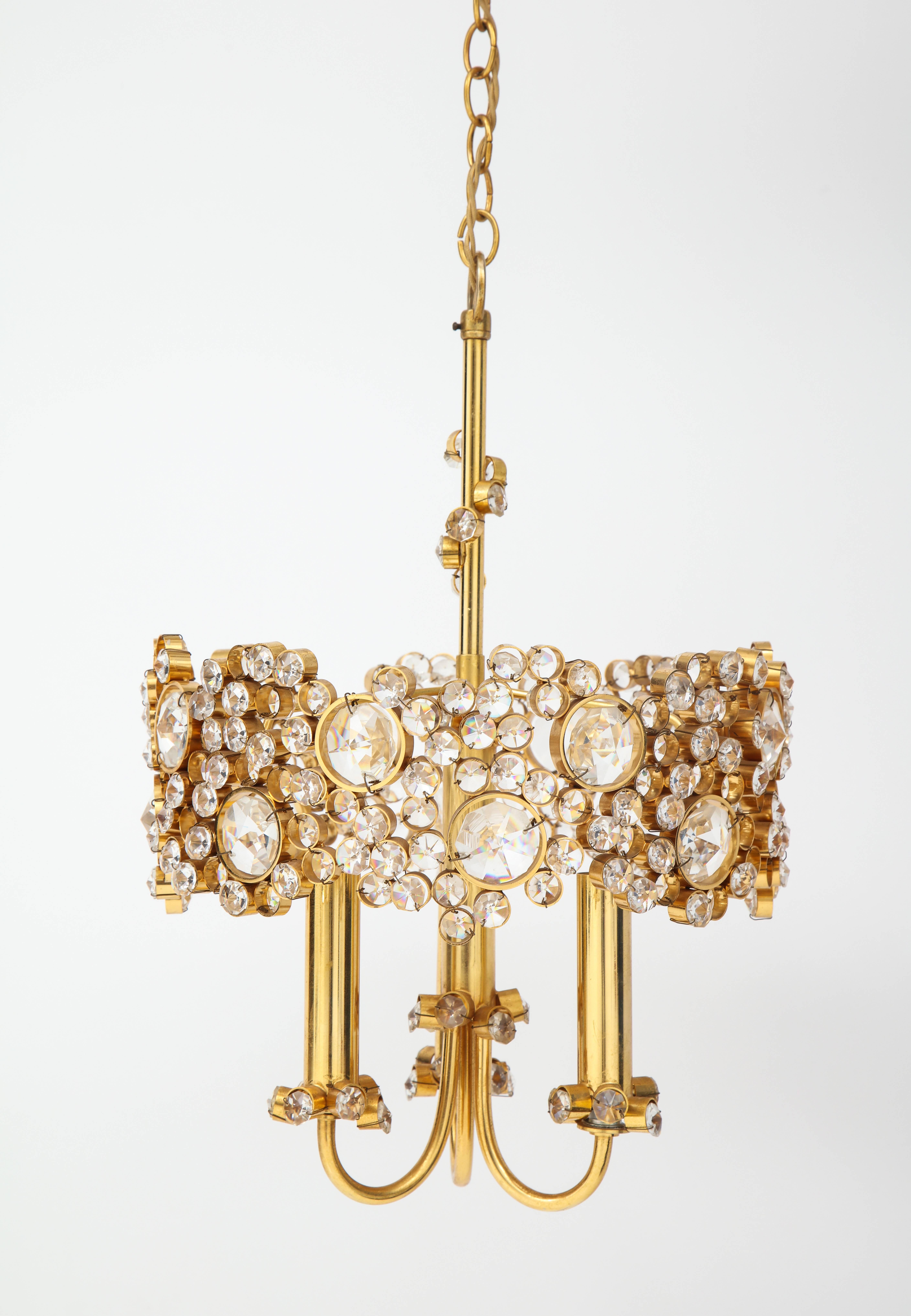 A gold-plated and faceted crystal chandelier with a central stem with climbing crystals and three gold plated arms decorated with crystals at the base. A jewel like piece, the crystals of varying sizes and shapes will provide beautiful light in any